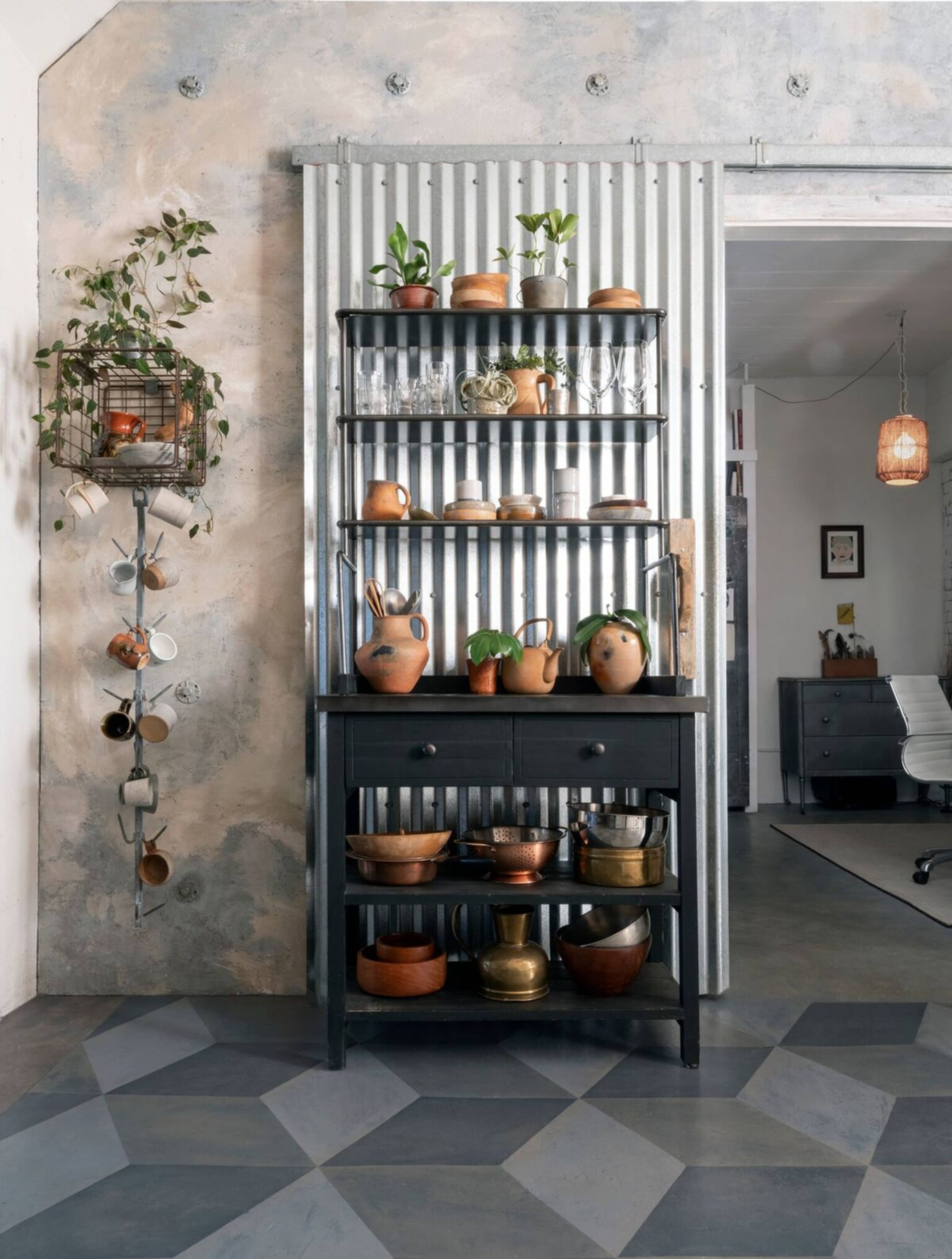 A modern kitchen with a black wooden shelving unit displaying glassware and ceramic pots against a textured wall and a patterned floor.