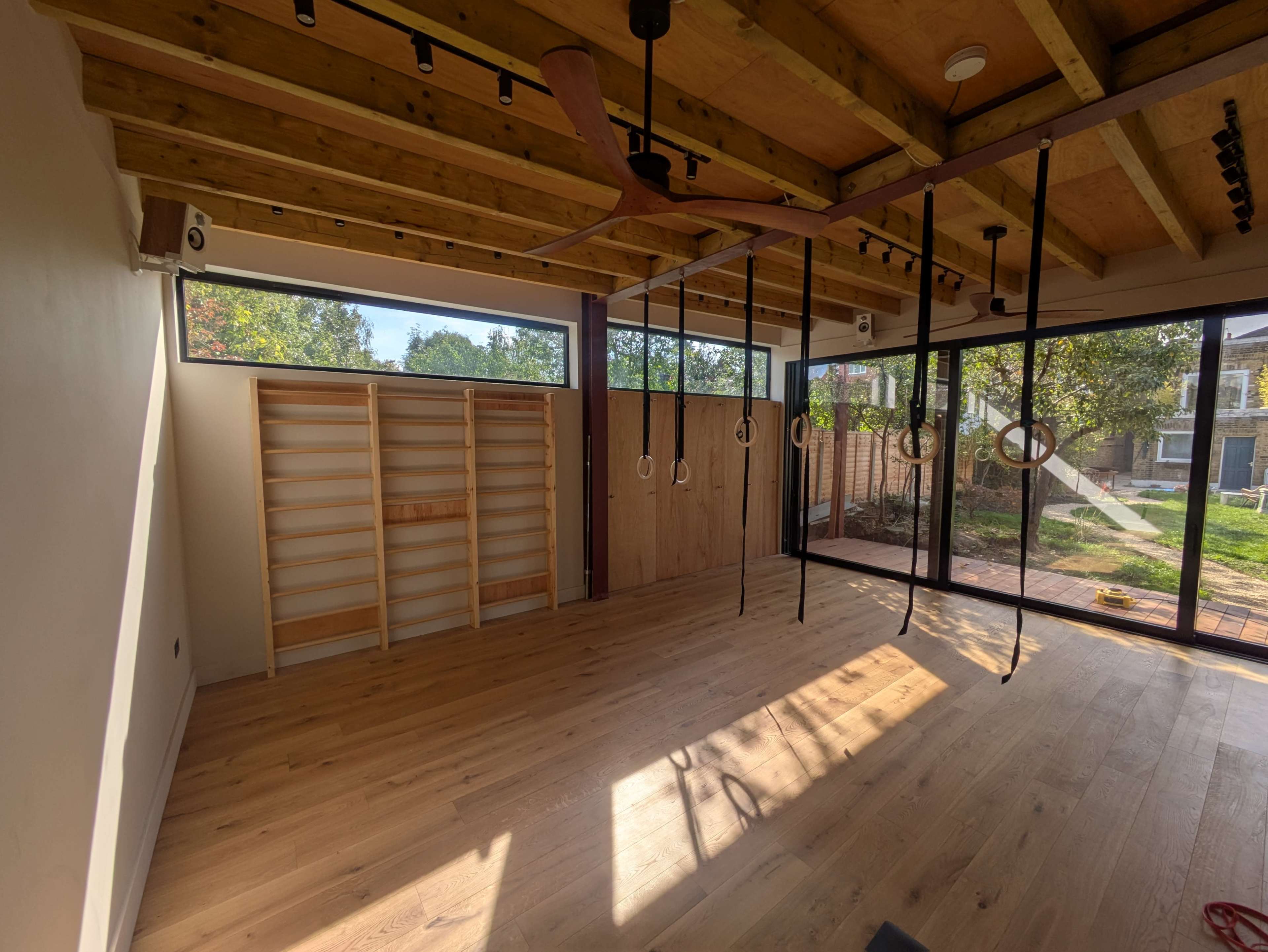 Light-filled movement studio in a garden, with natural wood accents Image in Leyton, London, ENG
