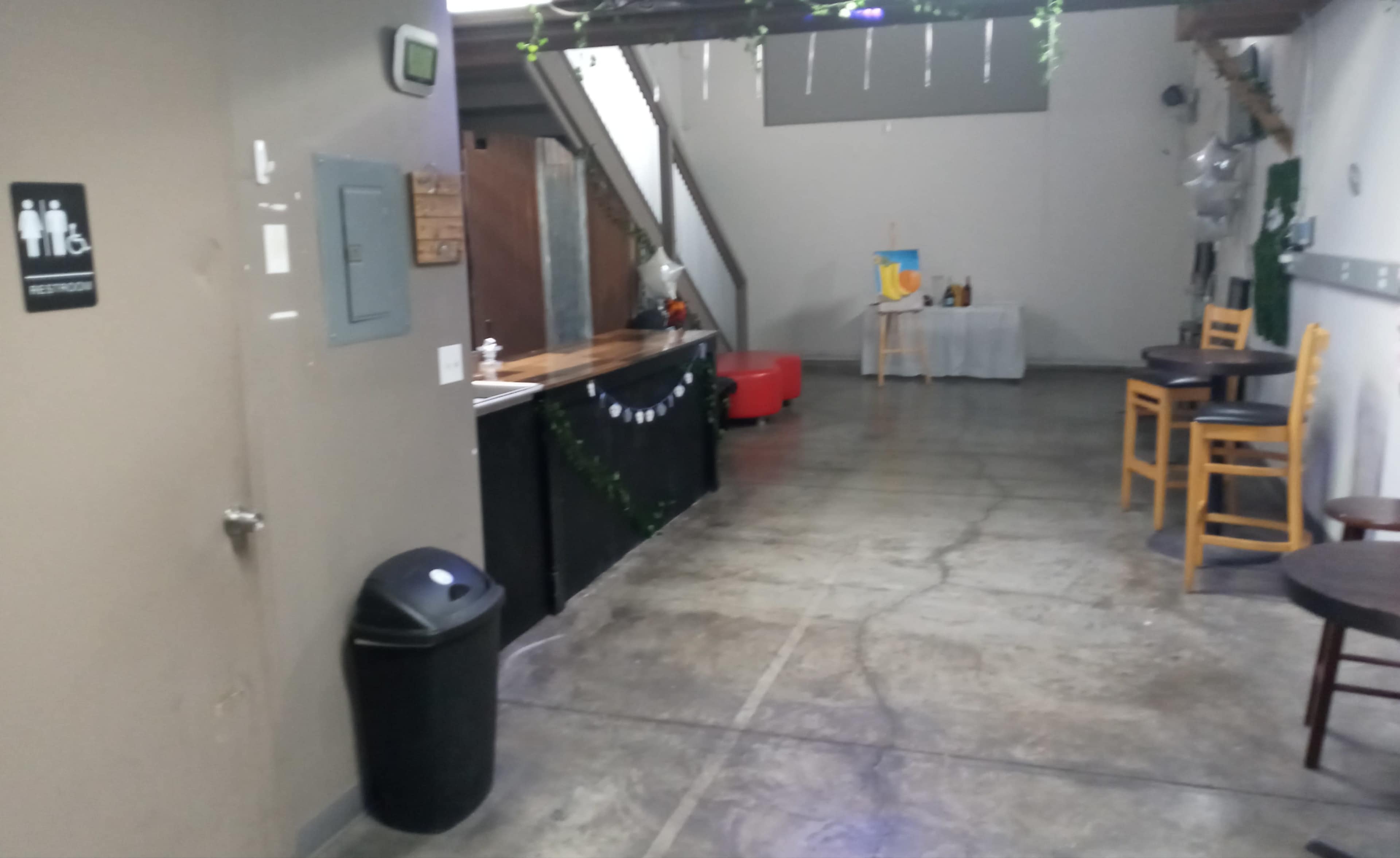 A spacious indoor area with a bar, seating, and restrooms to the left.