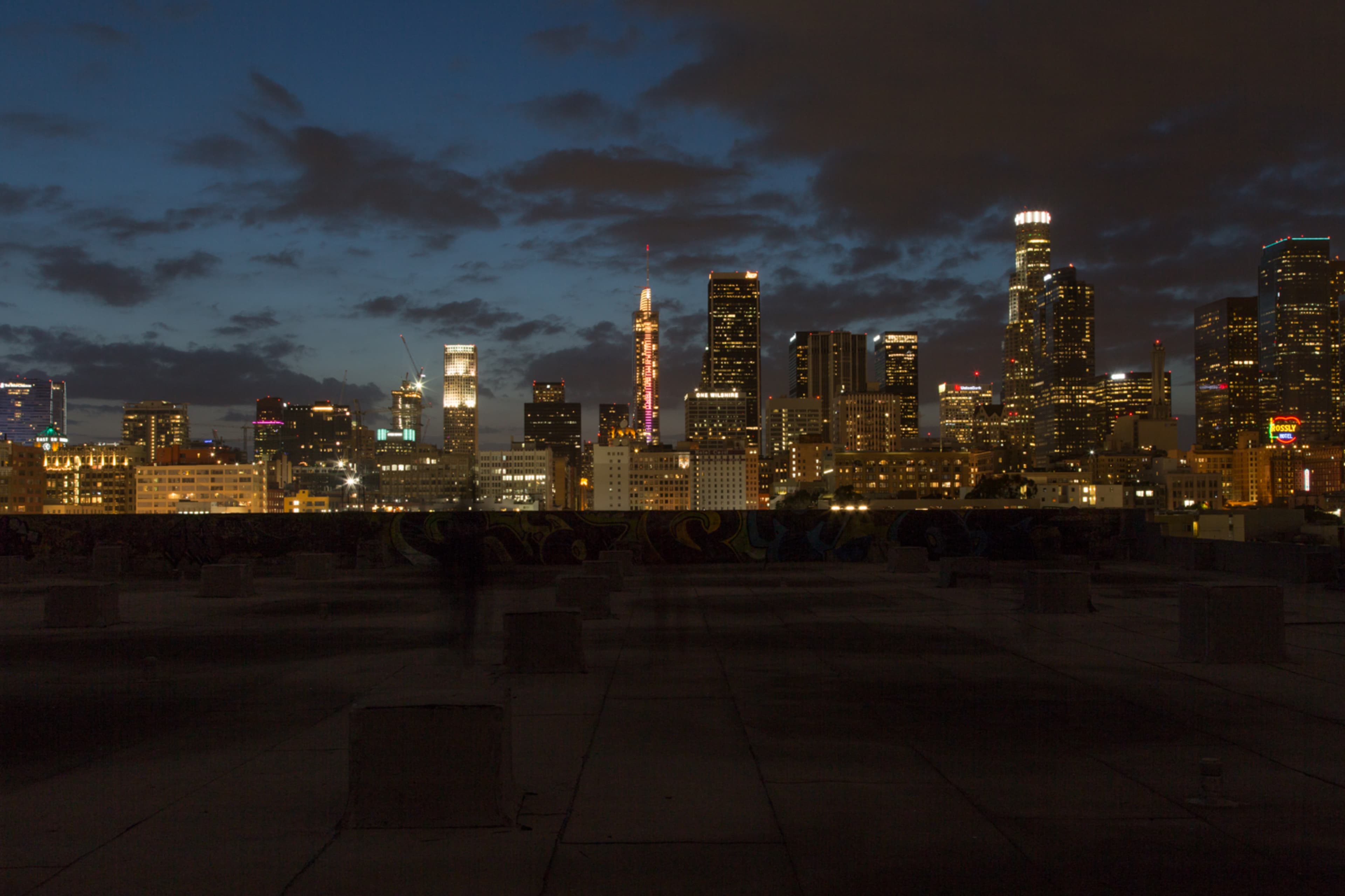 A nighttime cityscape of downtown Los Angeles, showcasing illuminated skyscrapers against a twilight sky.