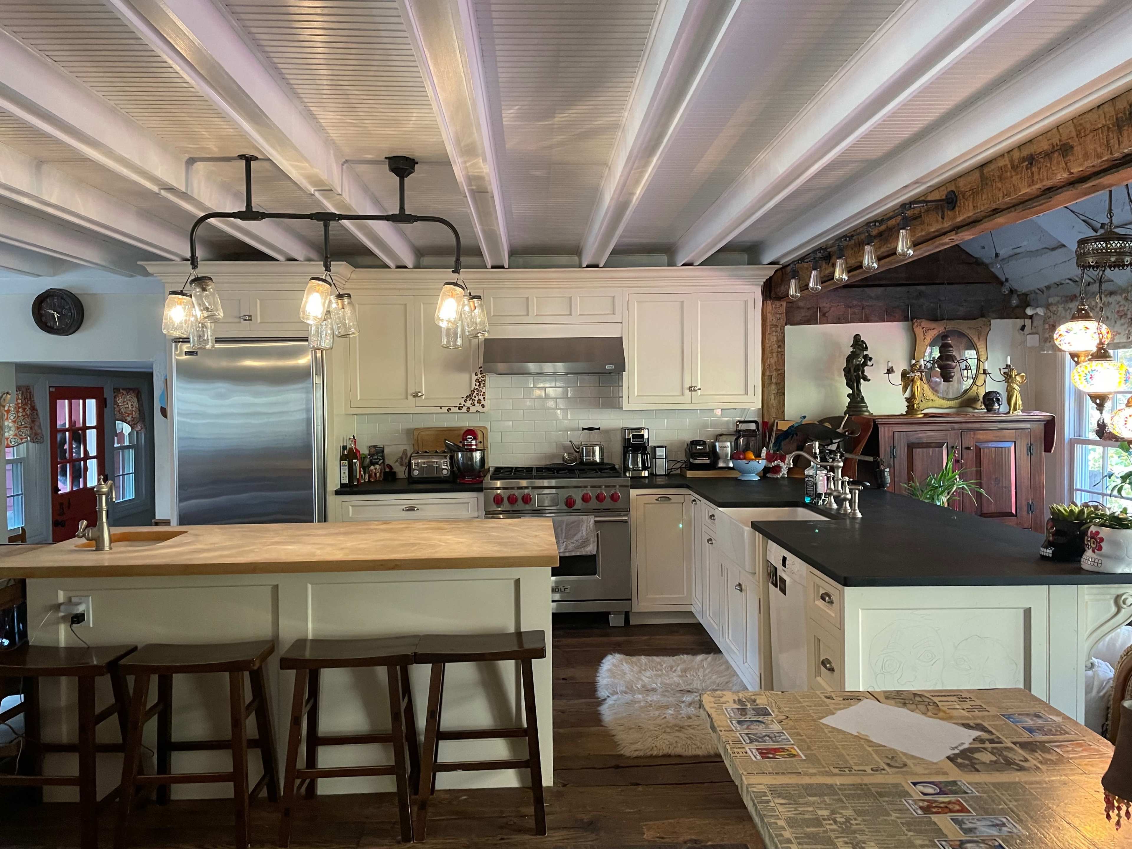The kitchen features white cabinetry, a stainless steel refrigerator, and a central island with wooden countertops and bar stools.