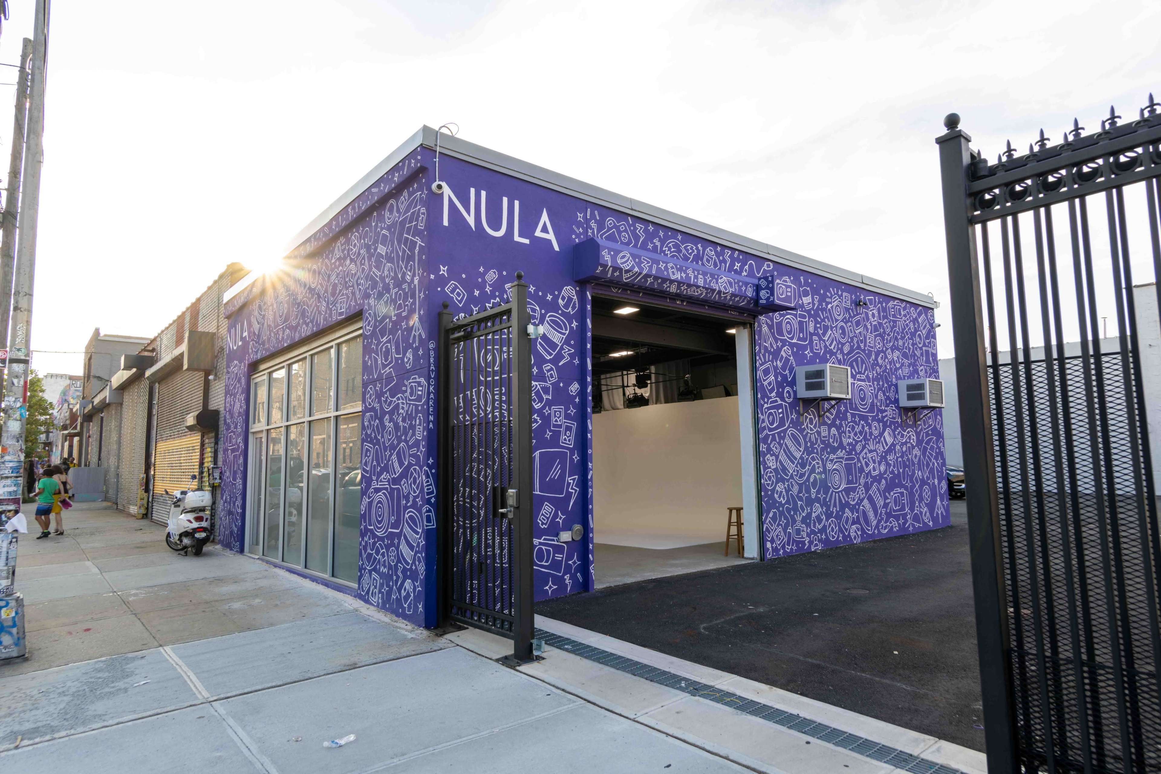 The exterior of a purple-painted building features a large mural and glass storefront, with the word "NULA" prominently displayed.
