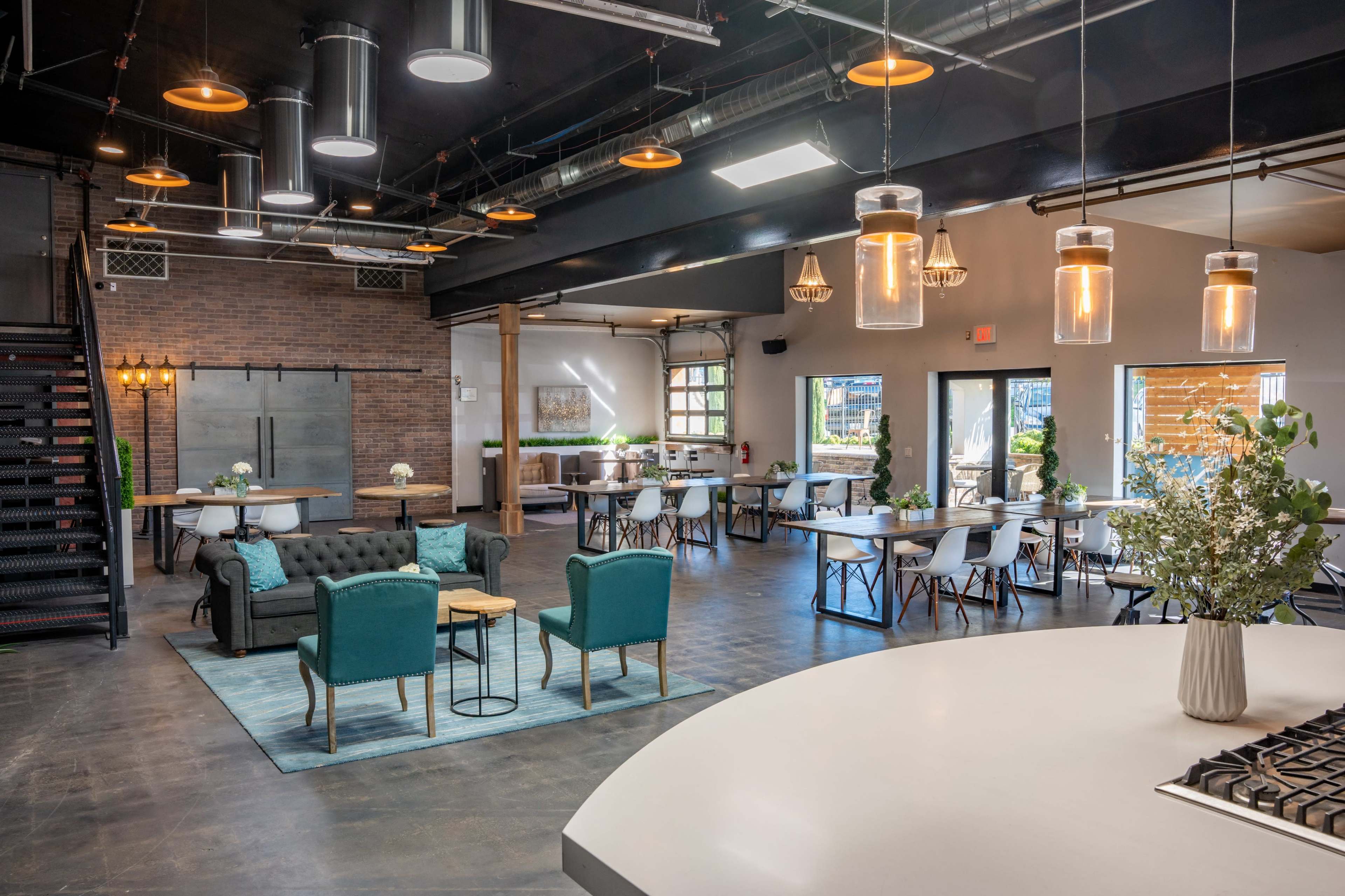 A spacious, modern event venue with various seating arrangements, large windows, and decorative lighting.