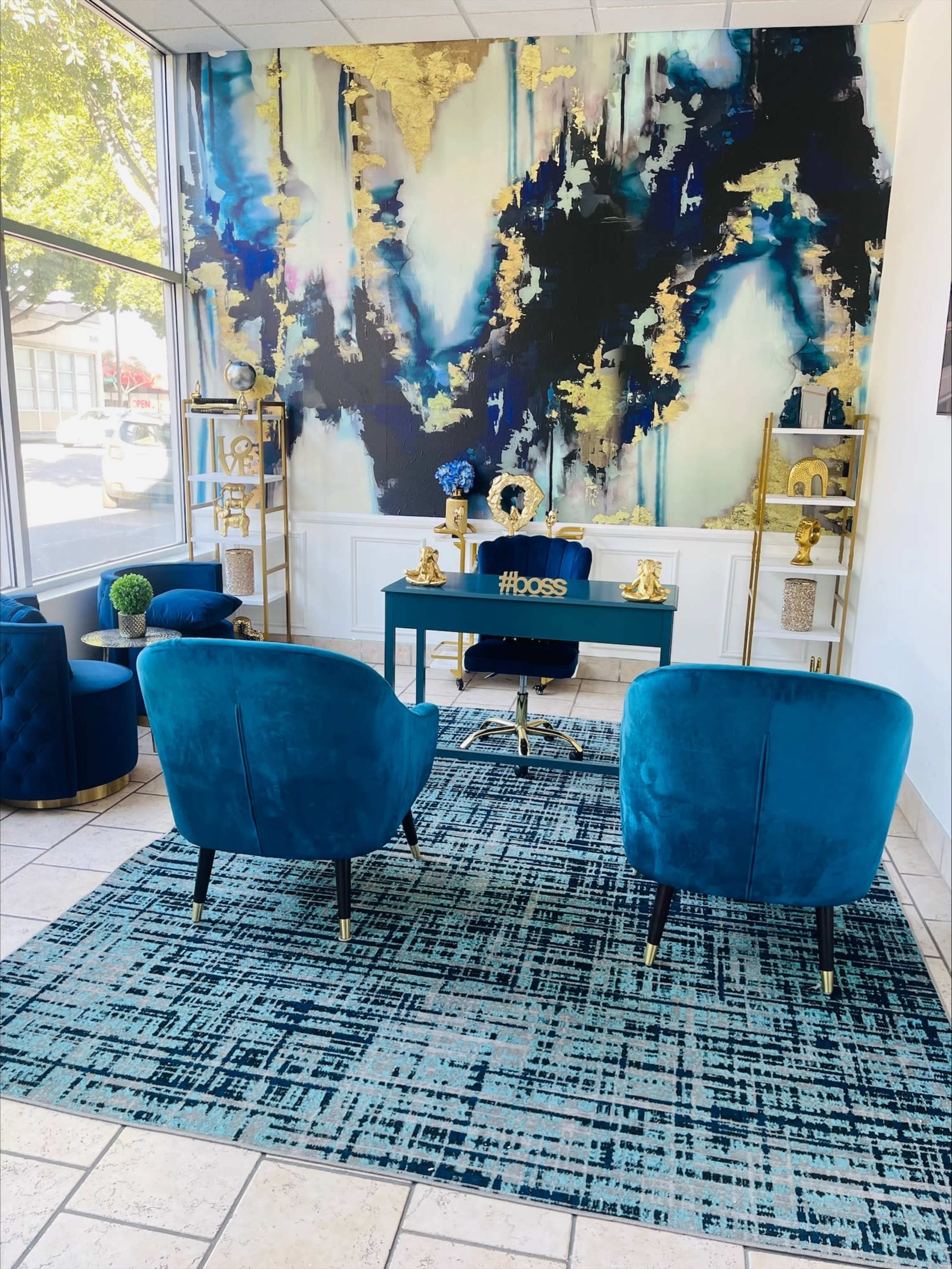 A modern office space features two teal chairs, a sleek desk with the hashtag "#boss," and a colorful abstract mural against the wall.