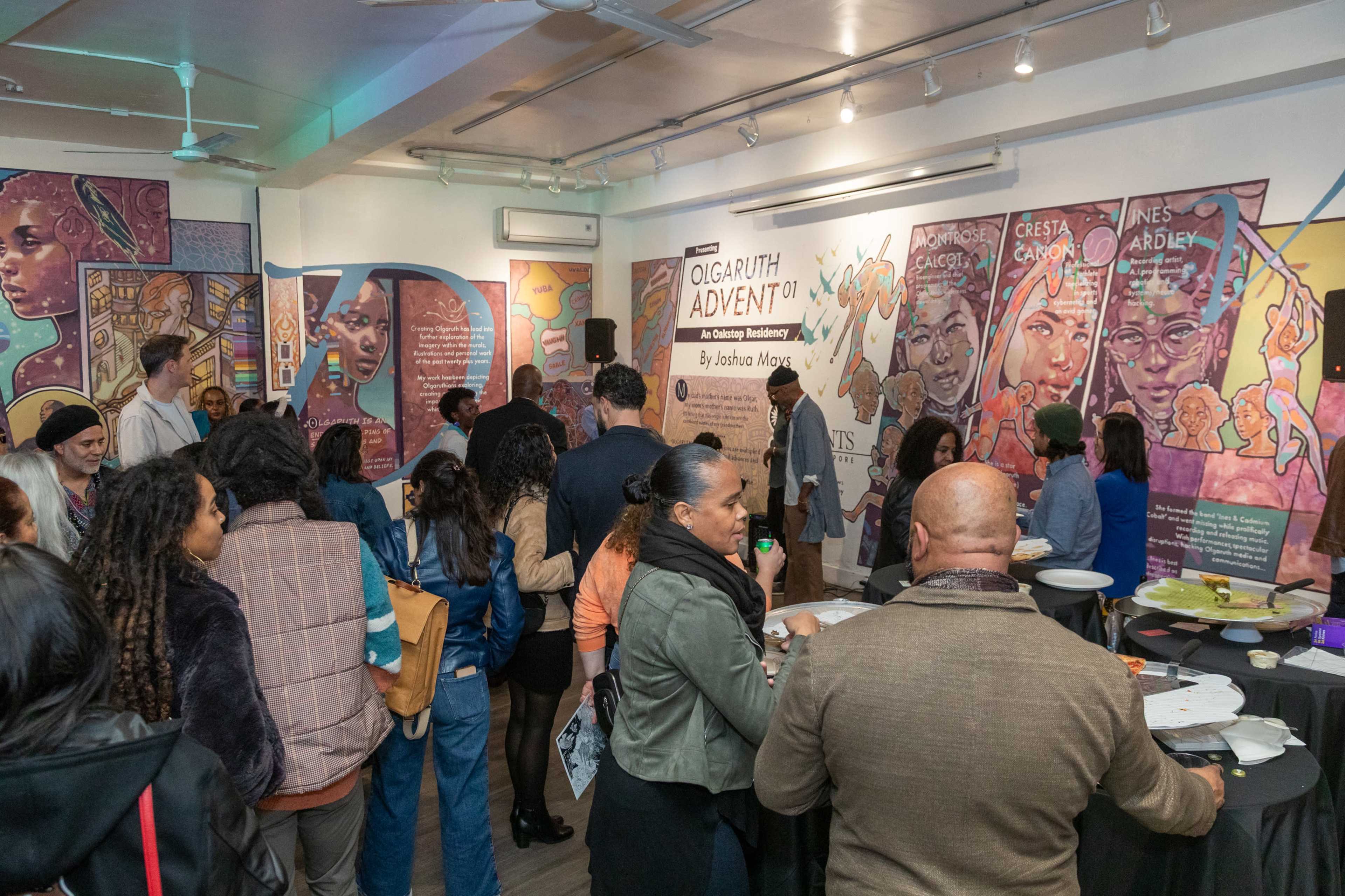 A diverse crowd gathers in an art gallery, engaging with a presentation while surrounded by large, colorful murals.