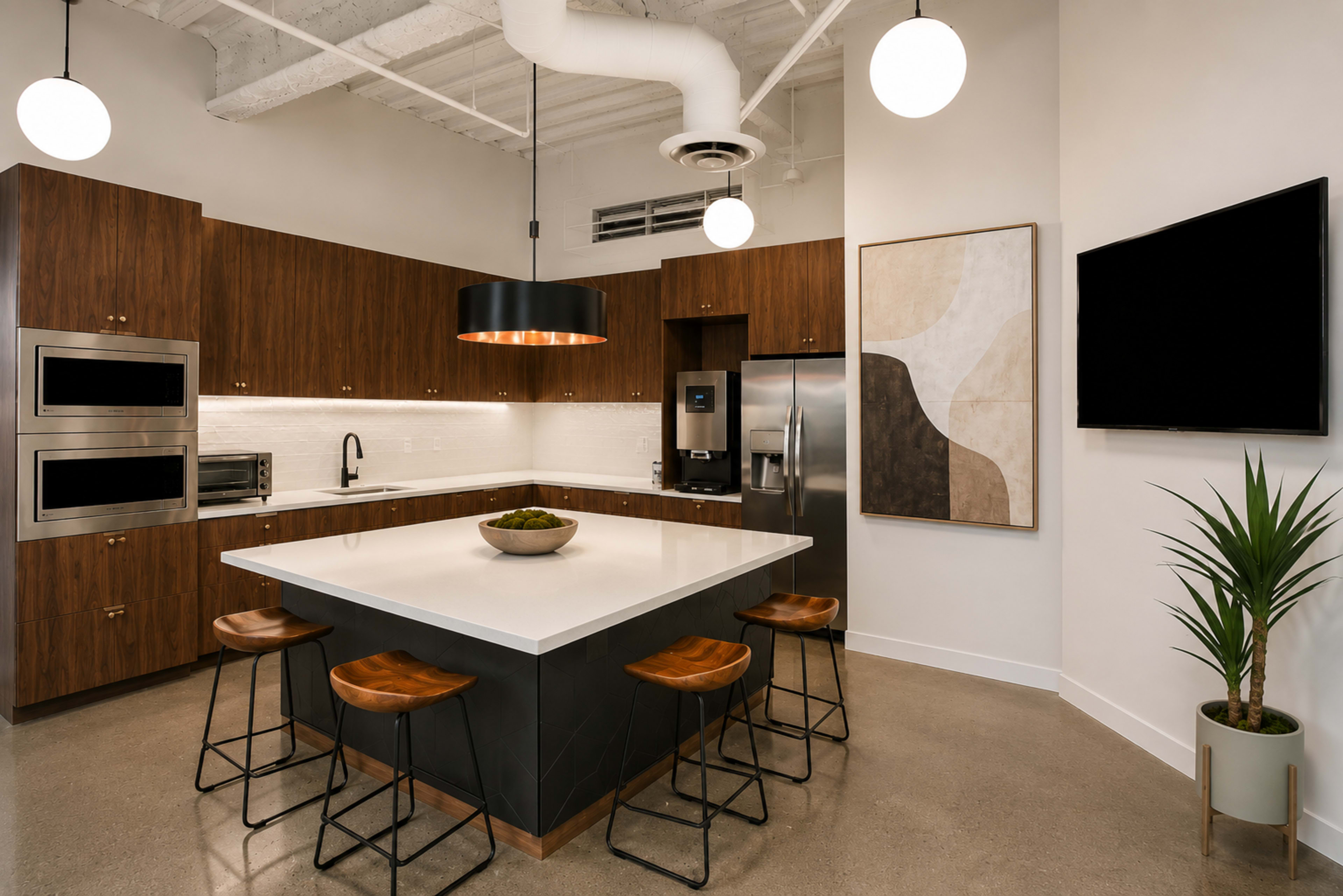The image depicts a modern kitchen featuring a large island with bar stools, sleek cabinetry, and appliances, complemented by pendant lighting and abstract artwork on the walls.