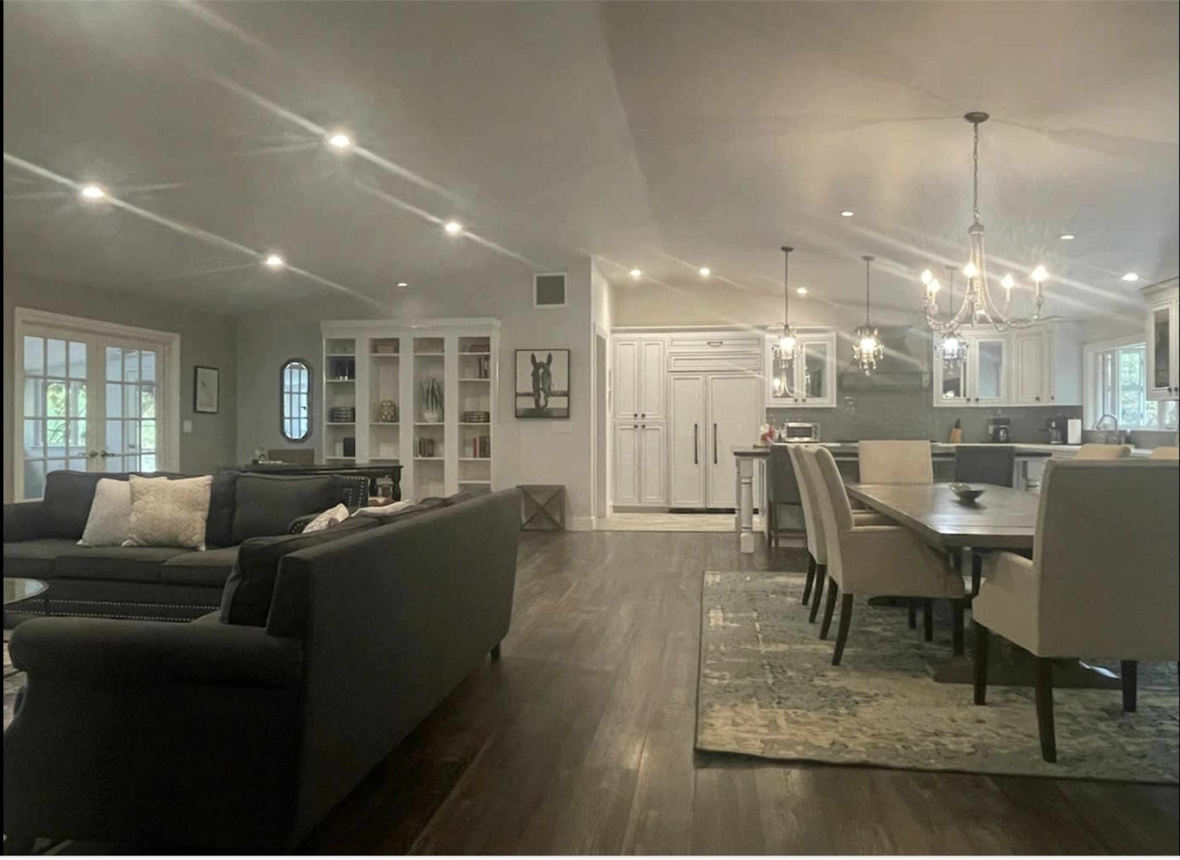 A spacious living area connected to a dining area, featuring modern furnishings and ample lighting.