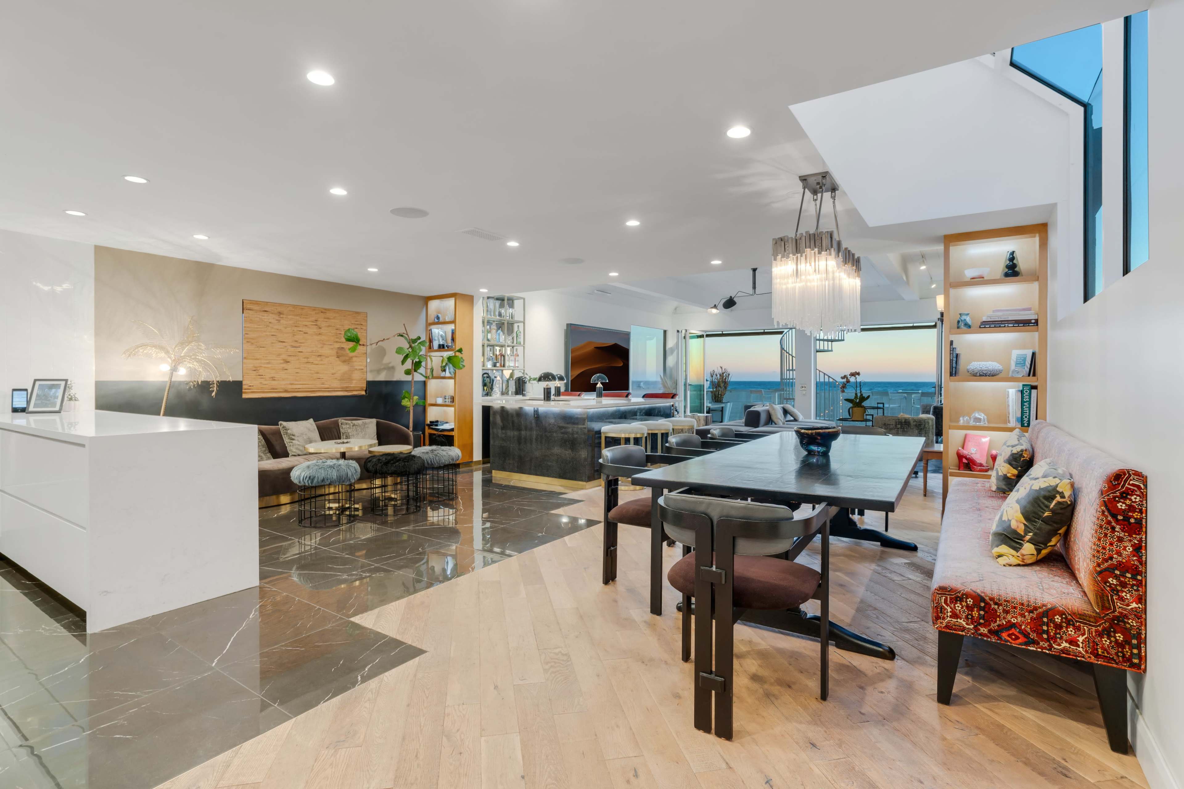 A modern living space featuring a dining area, a sleek kitchen, and a lounge with large windows overlooking the ocean.