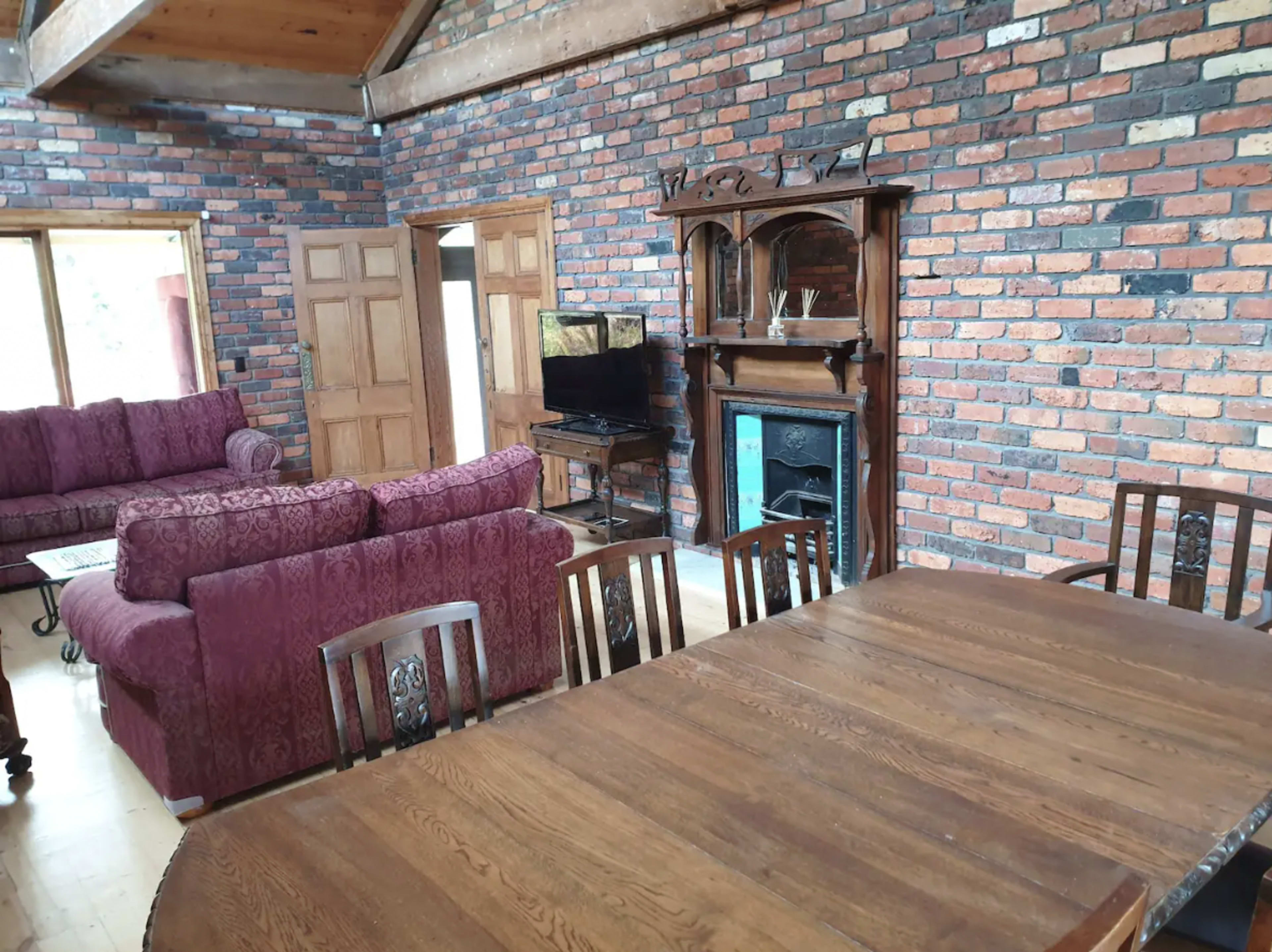 A spacious living area with a brick wall, wooden furniture, and a television.