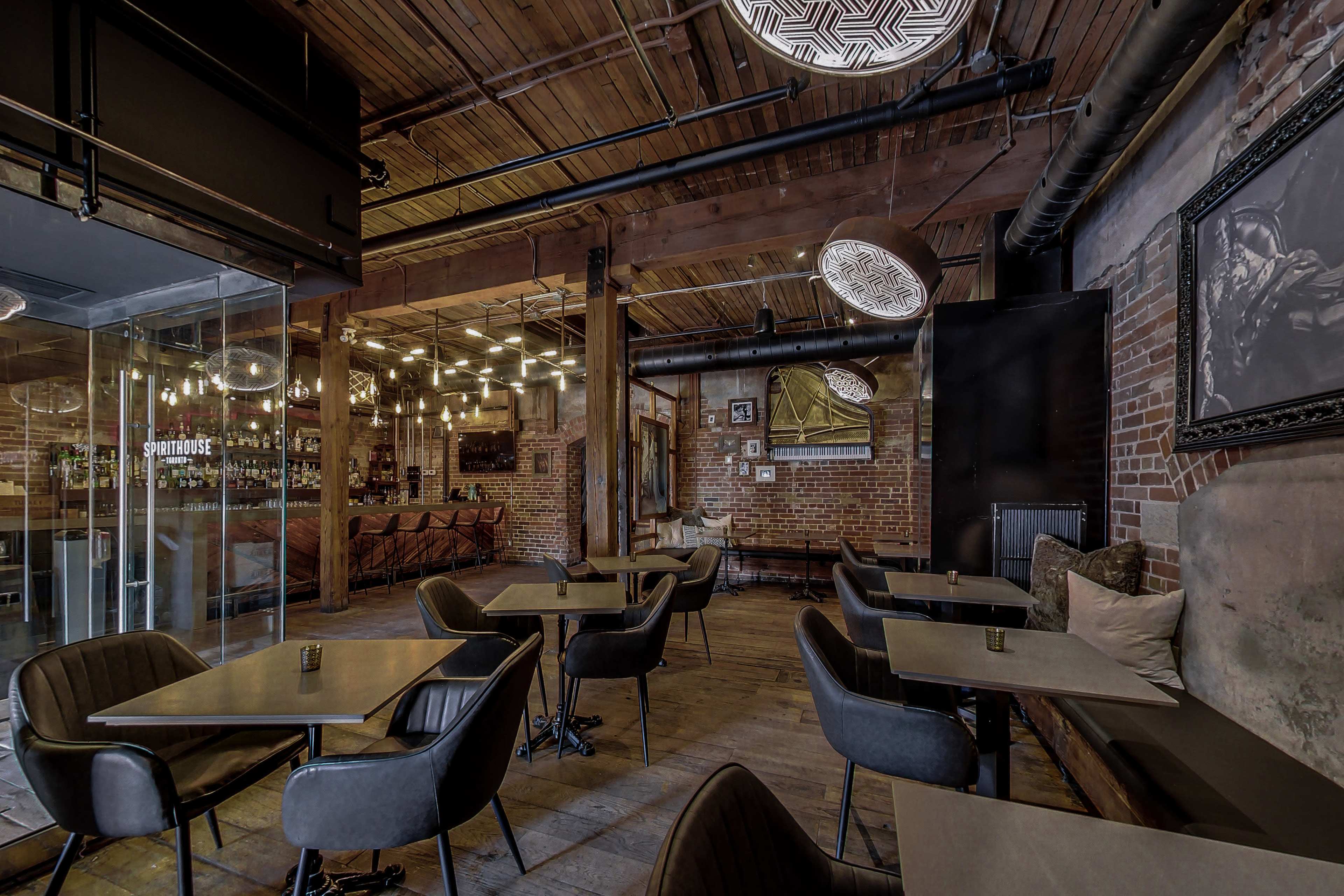 The image shows a rustic-style restaurant with wooden floors, exposed brick walls, and several tables arranged in a seating area.