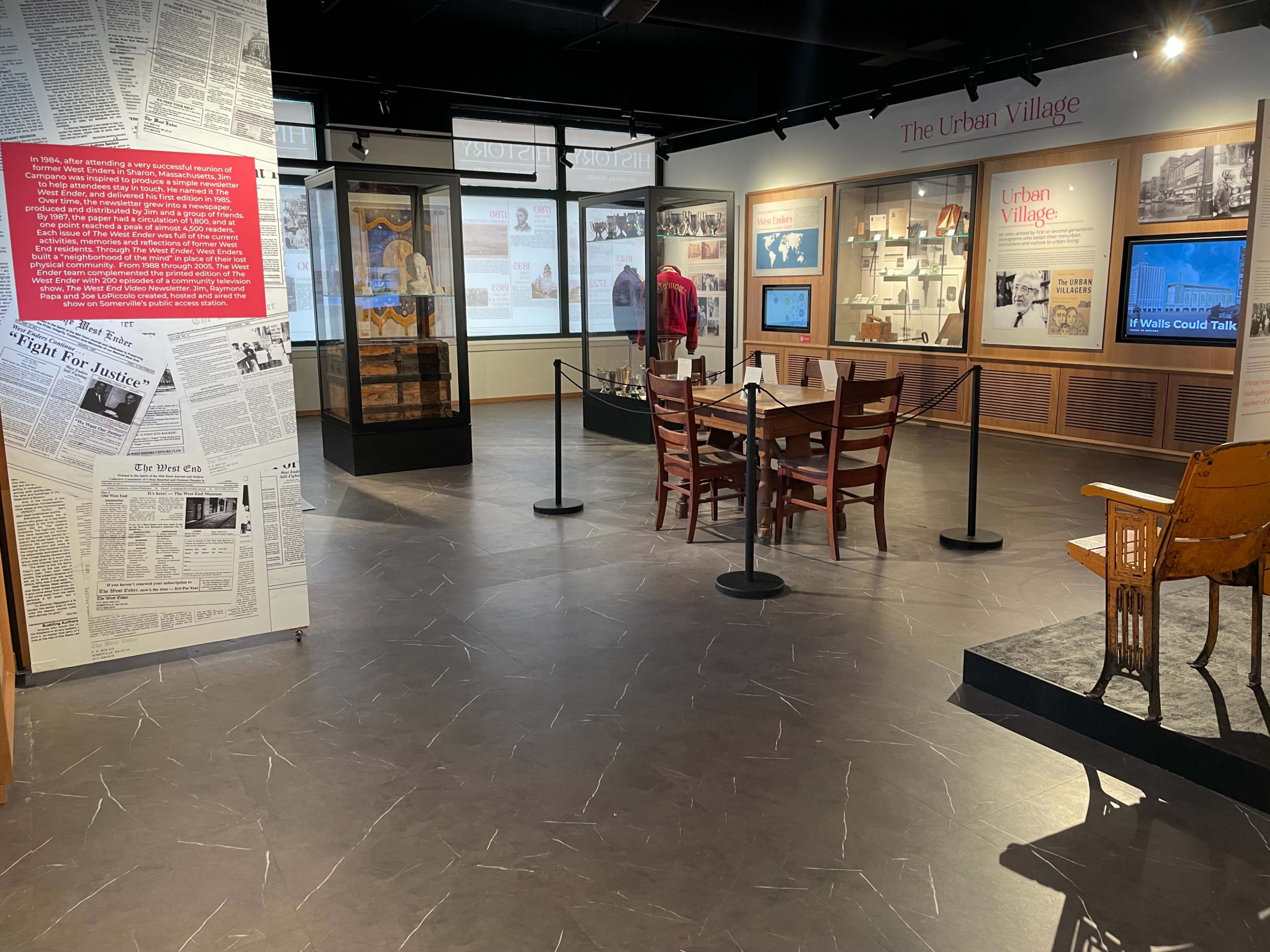 An exhibit space featuring informational displays, tables, and chairs arranged within a museum or gallery setting.