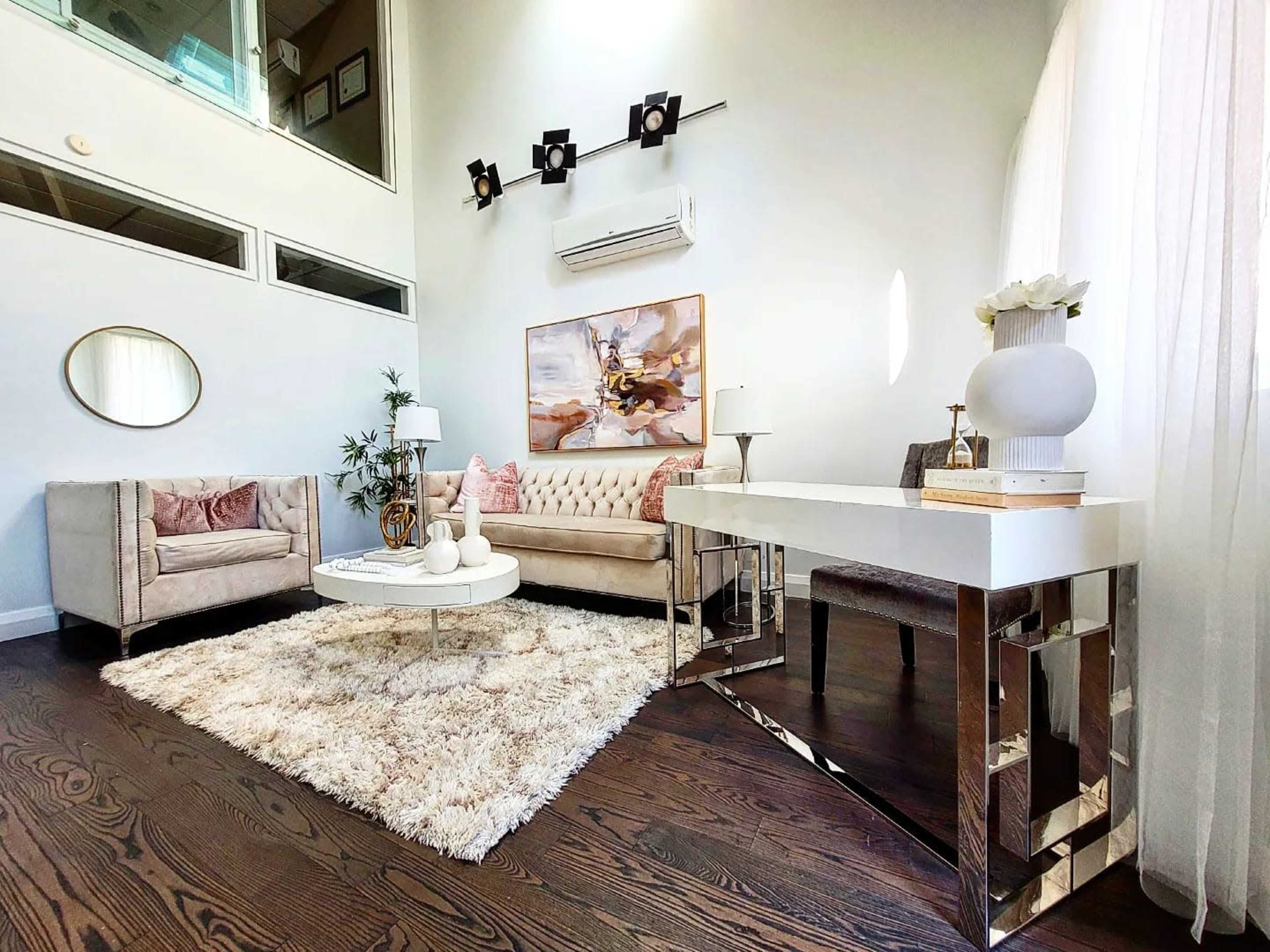 A modern living room with a beige sofa, a round coffee table on a fluffy rug, and a small white console table.