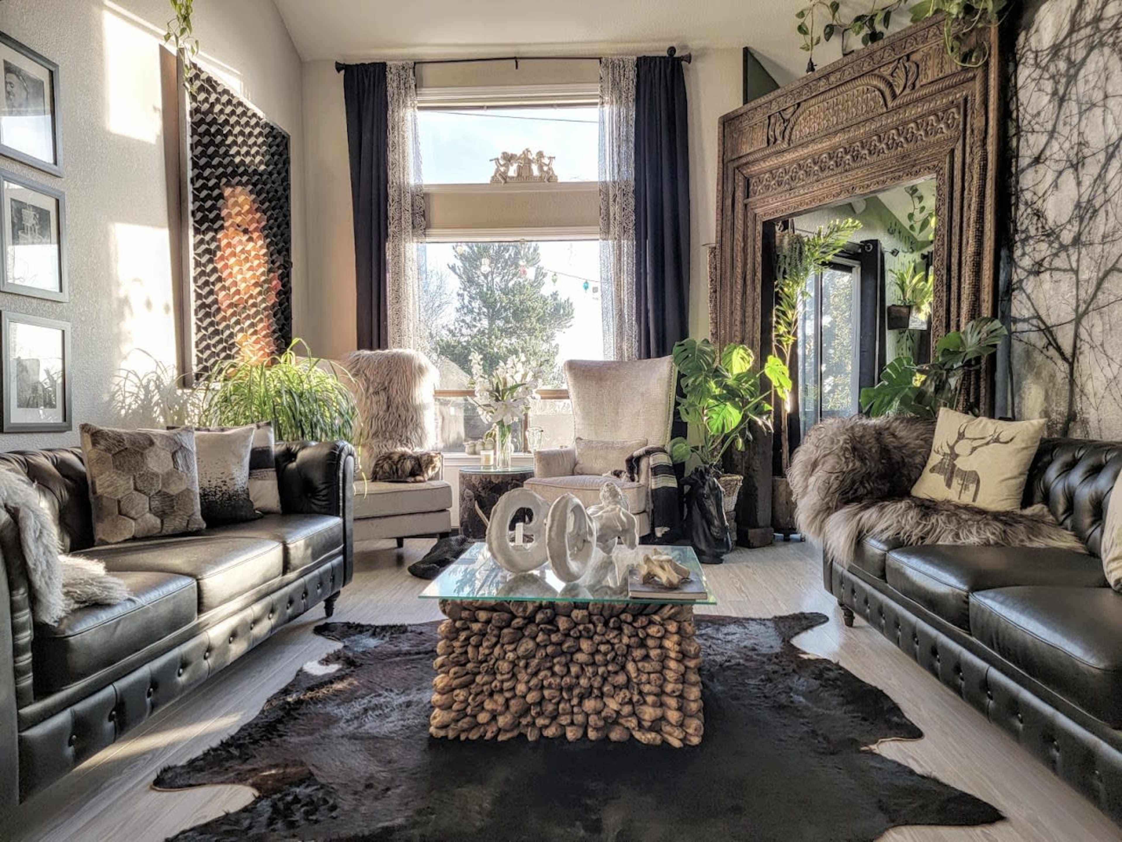 A stylish living room featuring two leather sofas, a glass coffee table adorned with decorative items, and large windows allowing natural light to illuminate the space.