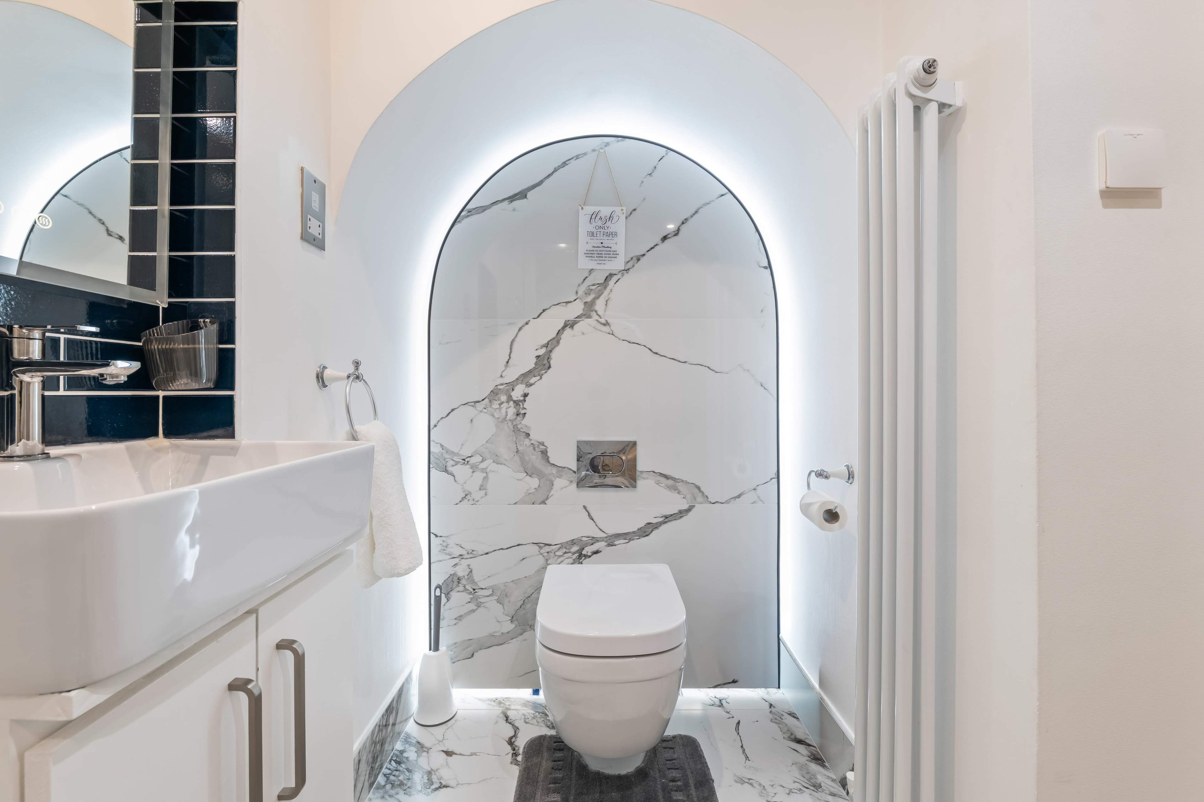The bathroom features a modern toilet set against a marble wall with an archway and ambient lighting.