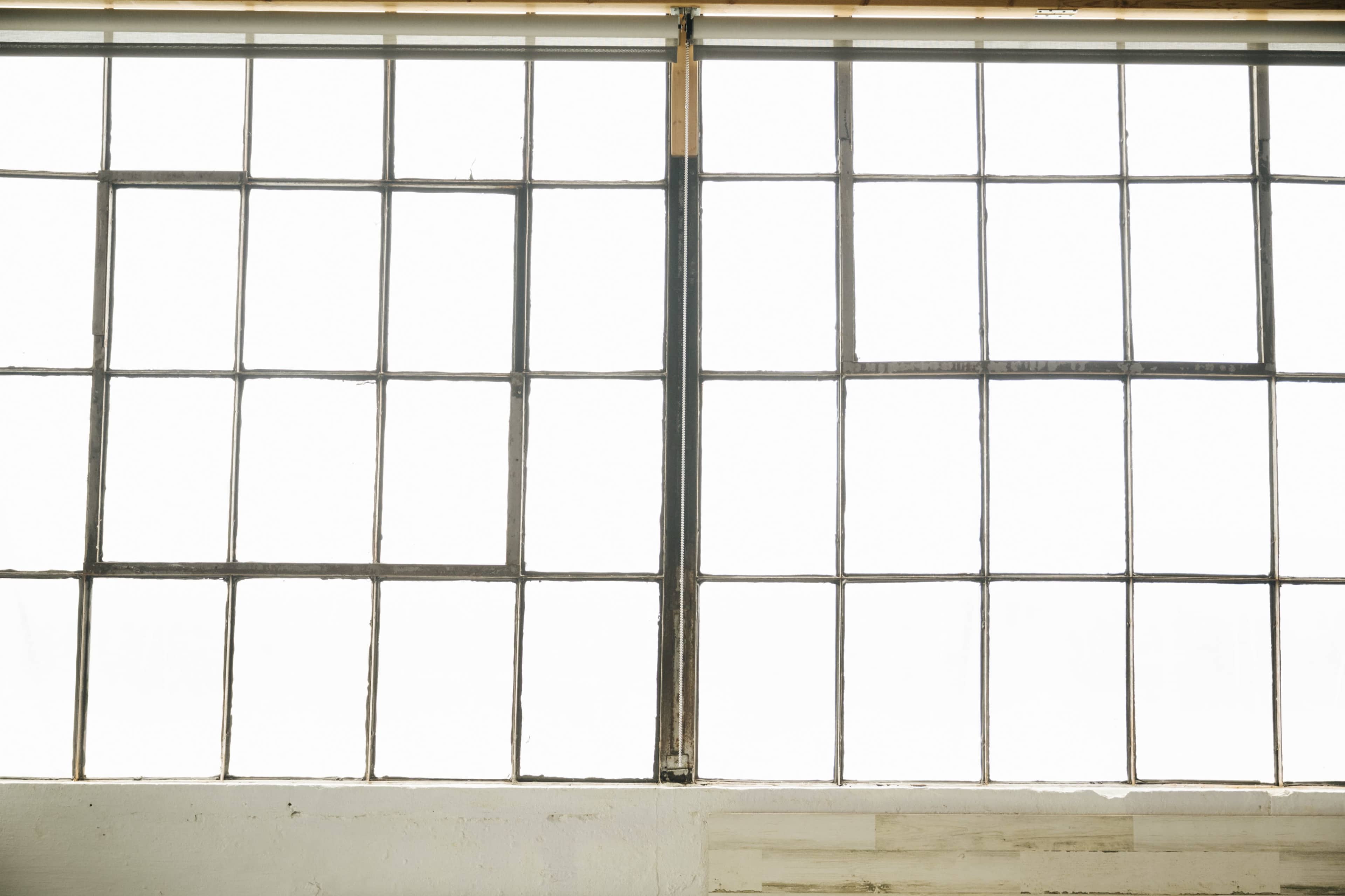 The image shows a set of large industrial-style windows with multiple panes, allowing diffused light to enter.