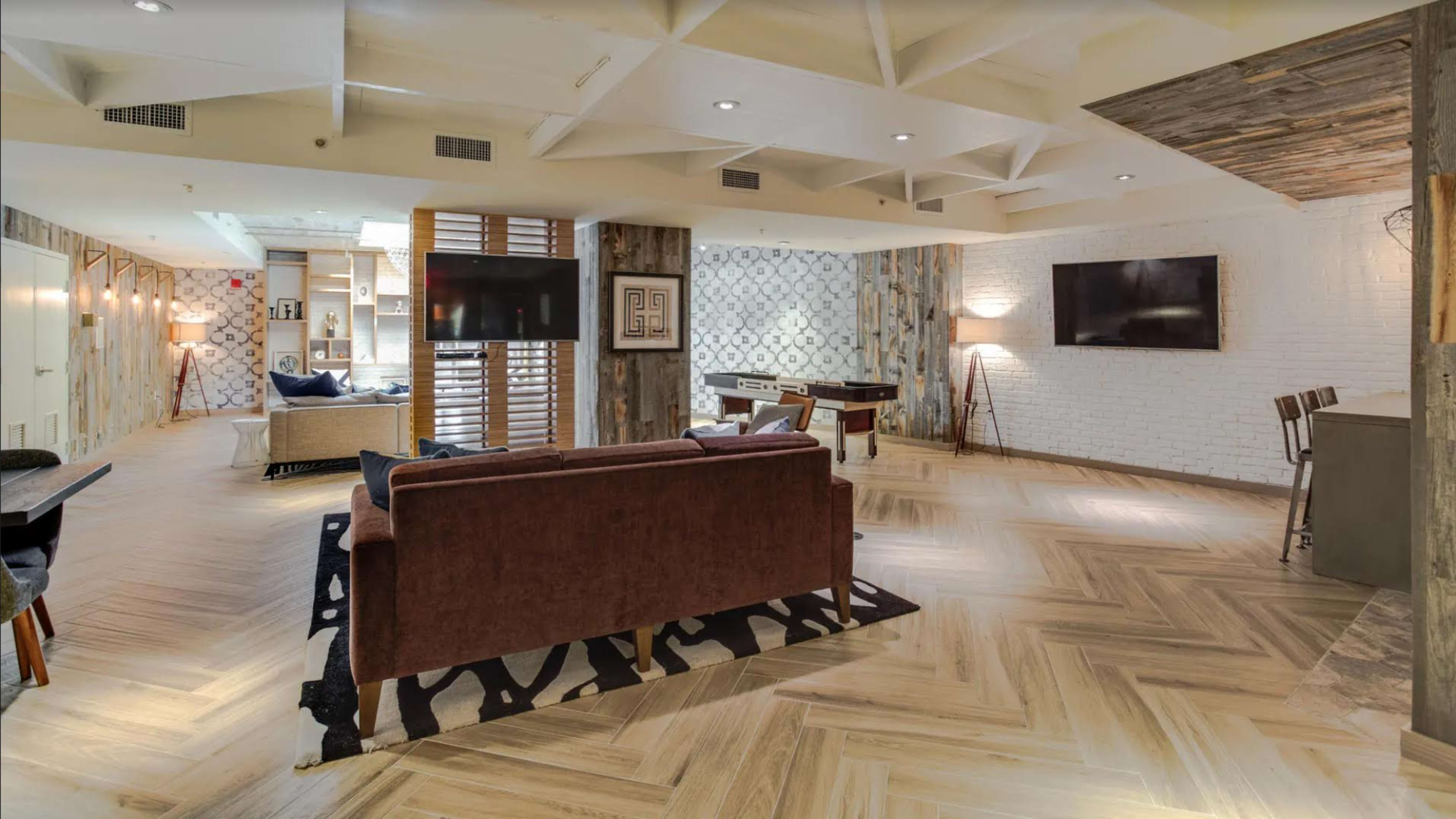 A modern living space with a combination of seating areas, wooden flooring, and decorative walls.