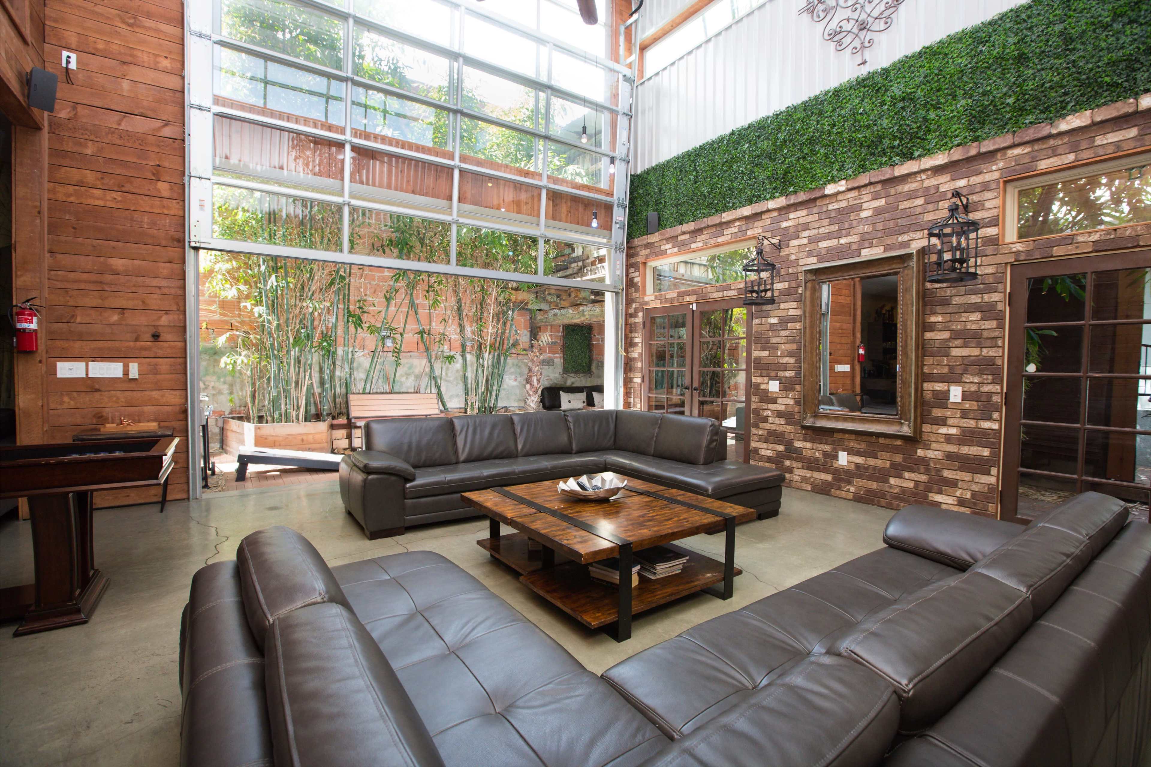 A spacious living area with a large sectional sofa, a coffee table in the center, and large windows allowing natural light to fill the room.