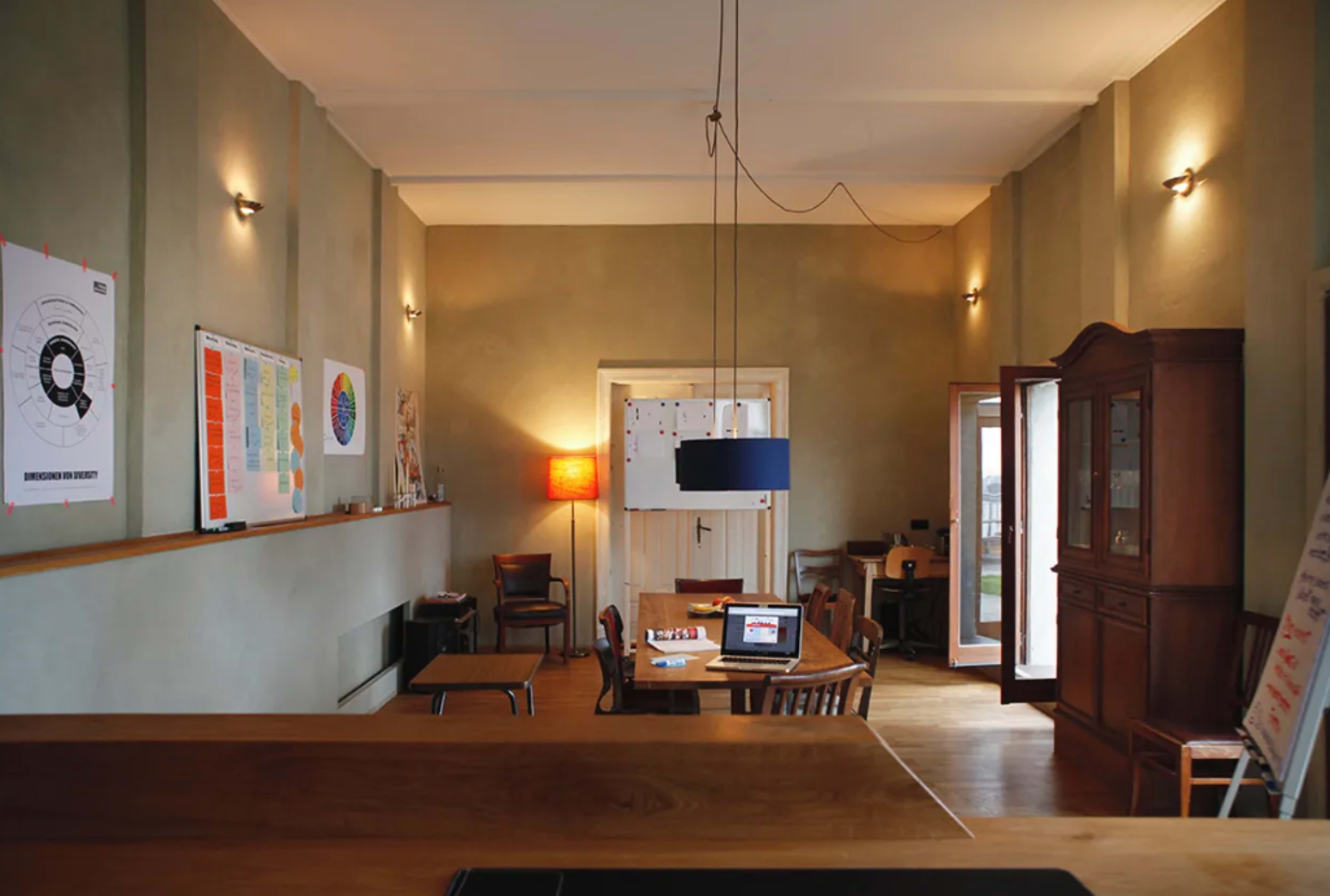 A spacious, well-lit office with a wooden countertop, a dining table, and various decorative elements on the walls.