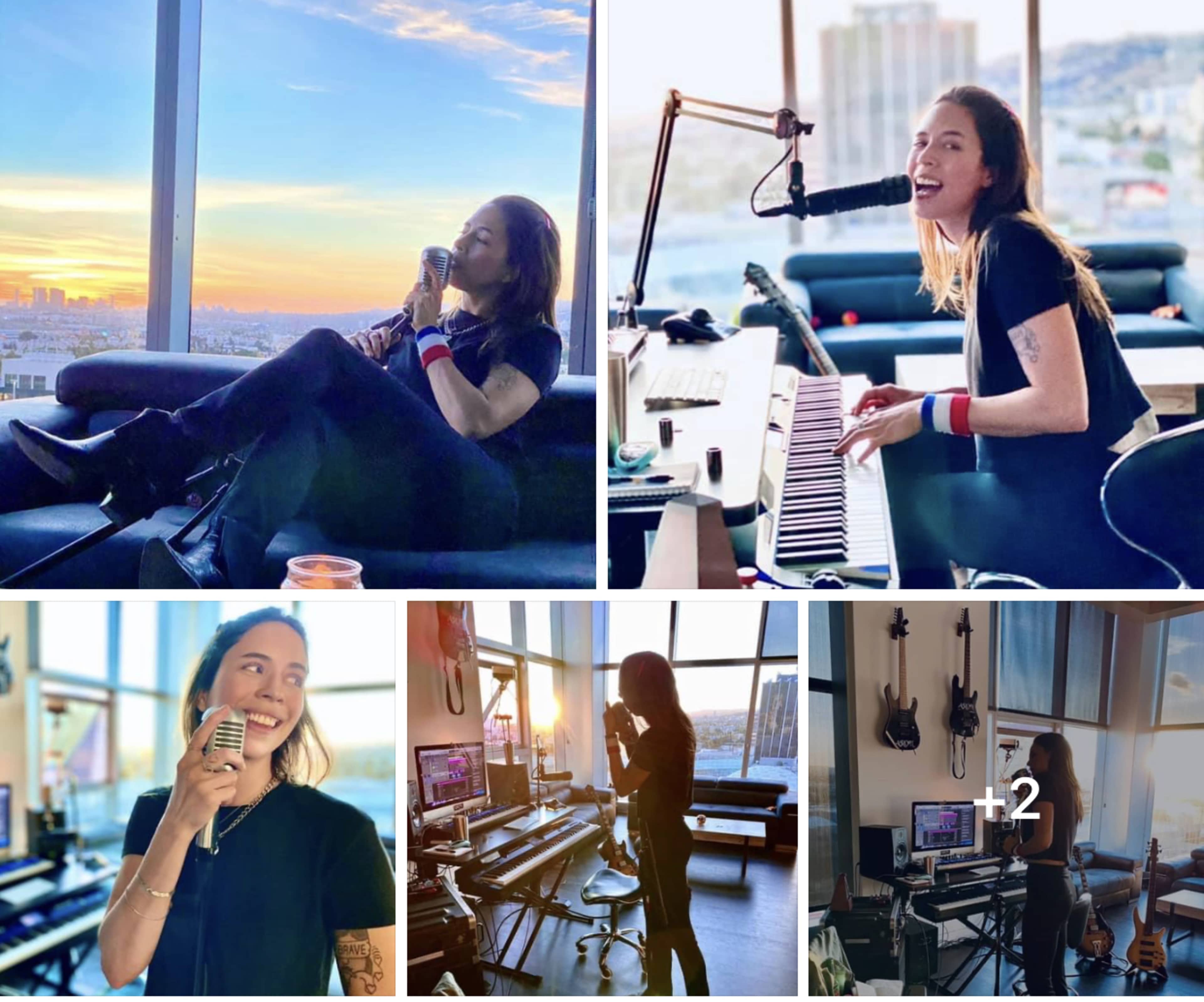 A musician interacts with her instruments and equipment in a well-lit studio with large windows showing a city skyline at sunset.