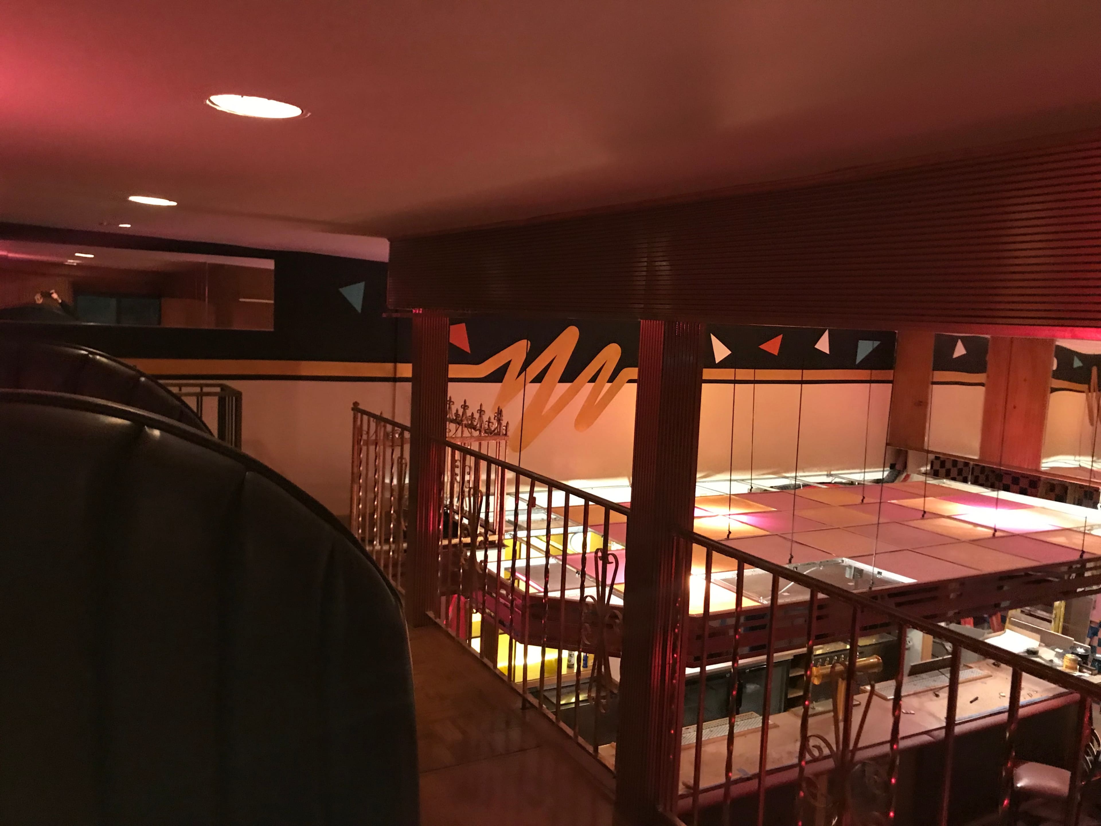 A dimly lit, colorful interior of a restaurant or bar featuring a mirrored ceiling and geometric wall designs.