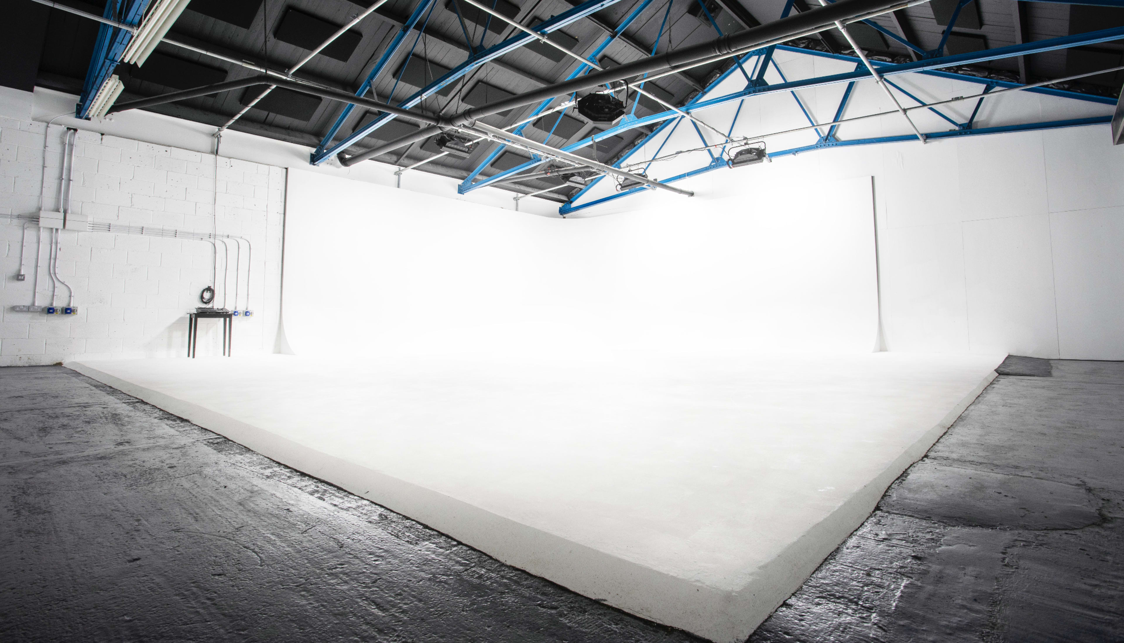 A spacious, well-lit studio with white walls and a sloped white floor.