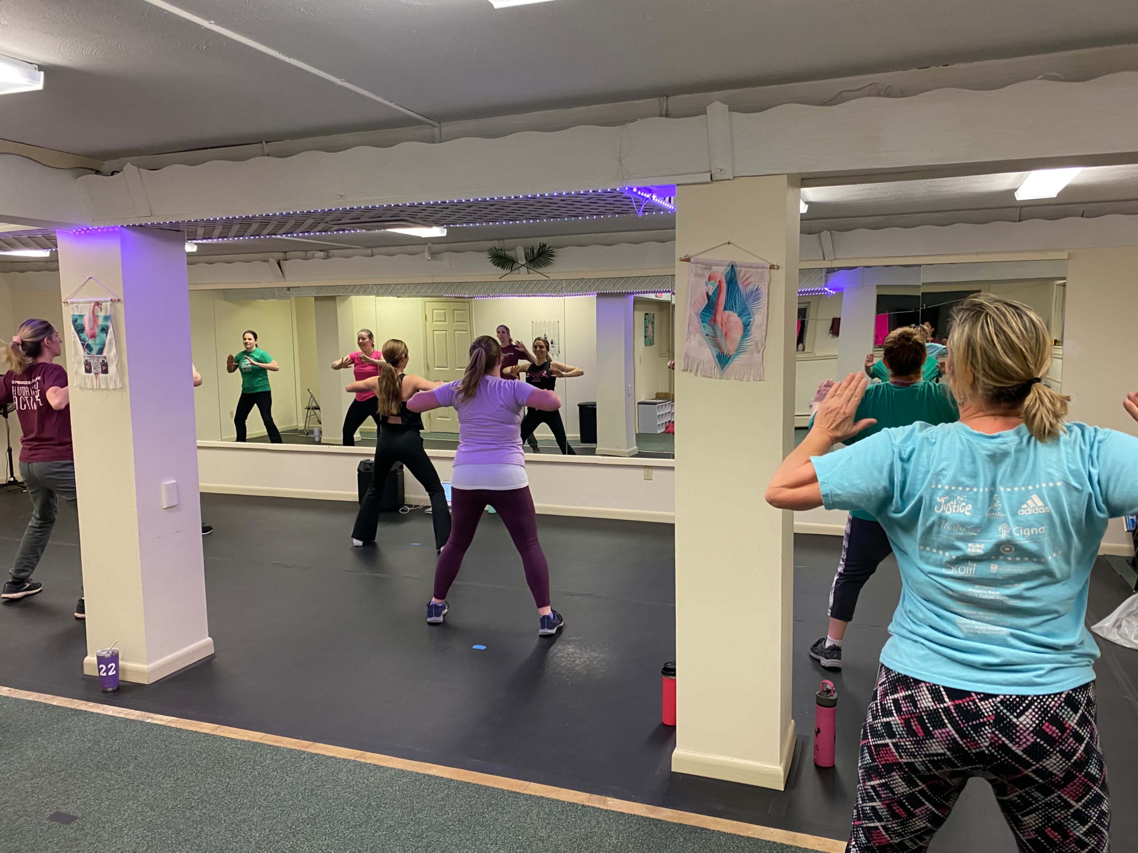 A group of people is participating in a fitness class in a mirrored studio.