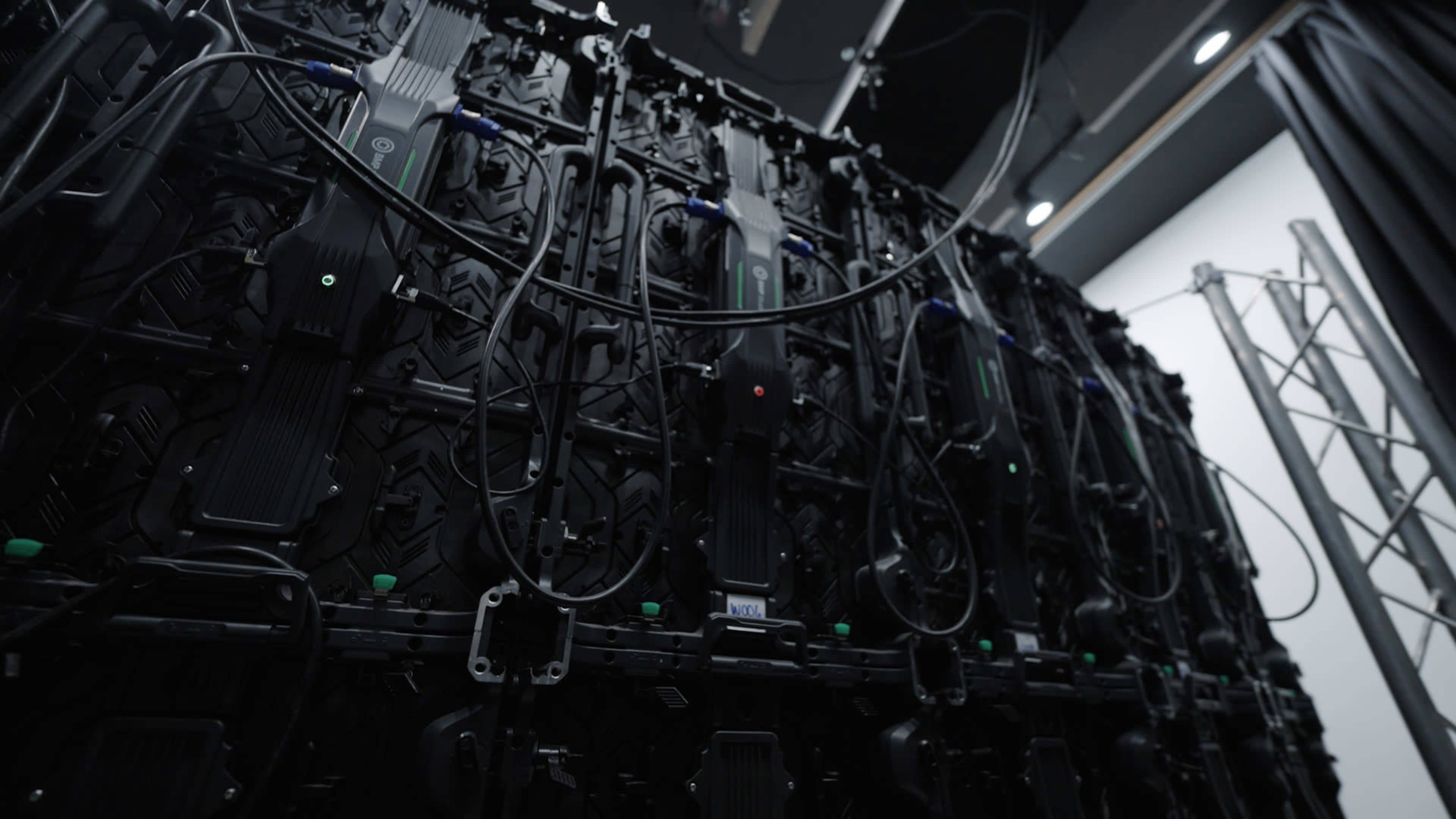 The image shows a large wall of interconnected display panels with various cables and connectors visible.