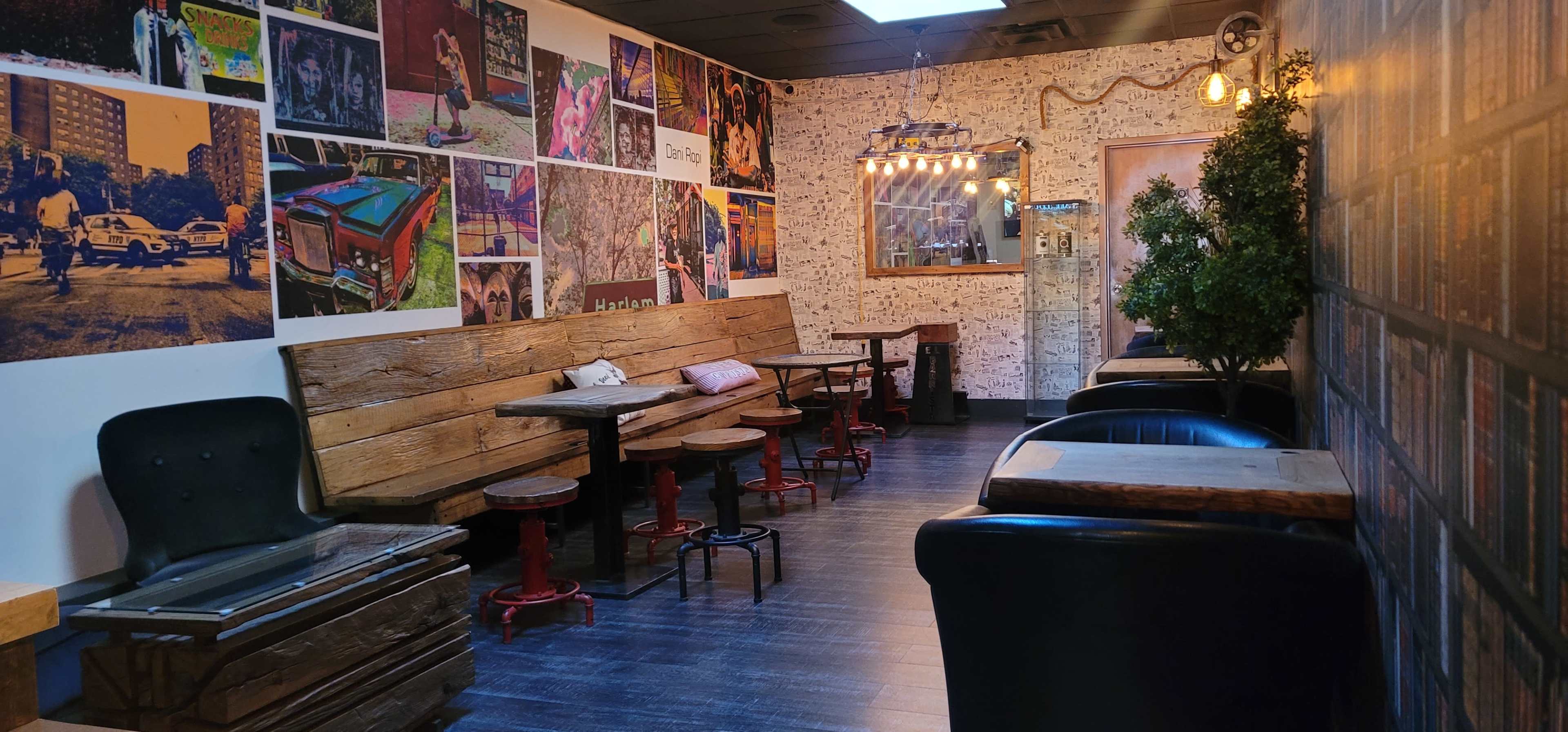 A cozy café interior with wooden benches, small round tables, and wall art featuring colorful photographs.