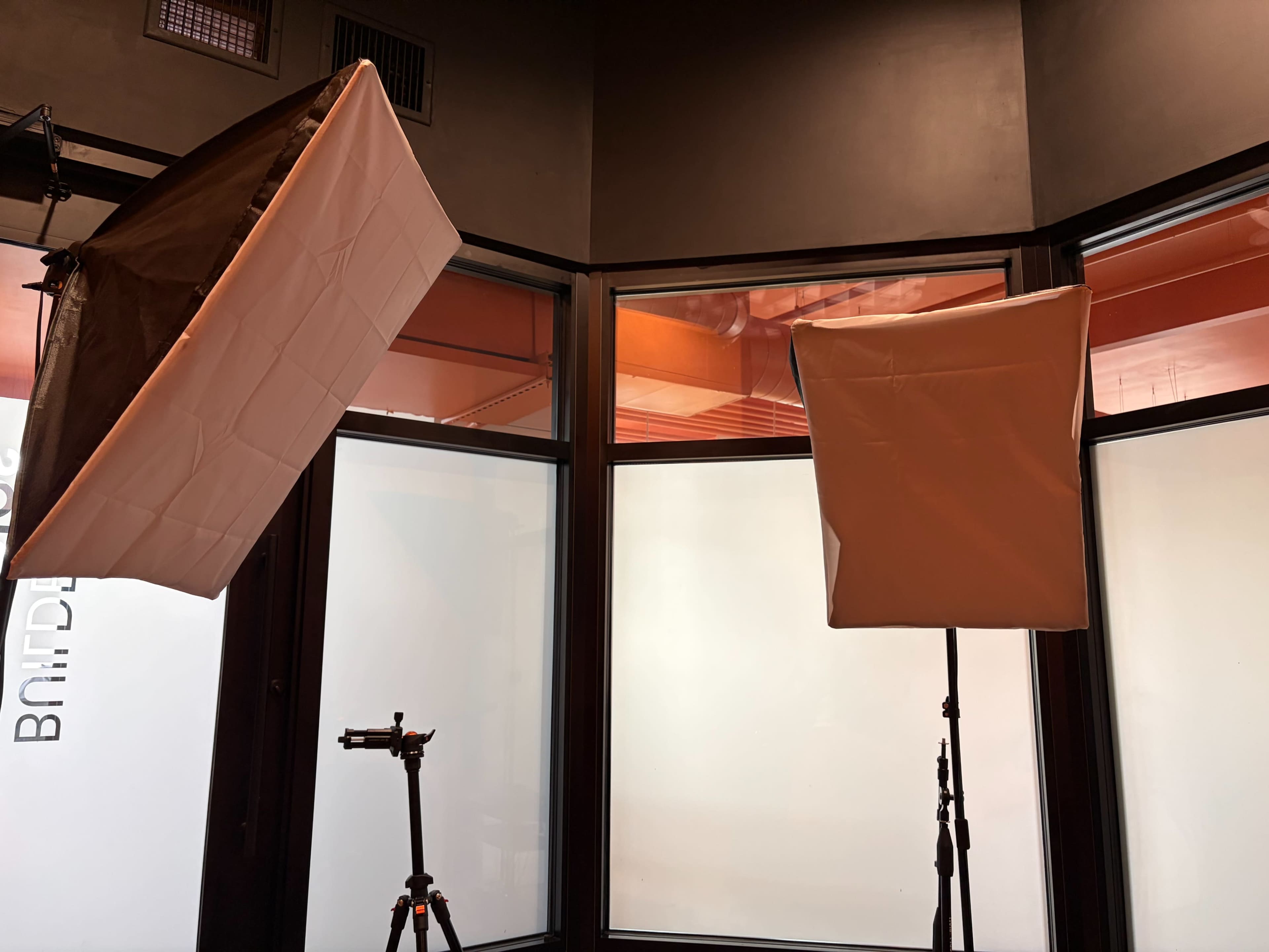 The image shows two softbox light setups positioned near large windows in a room with dark walls.