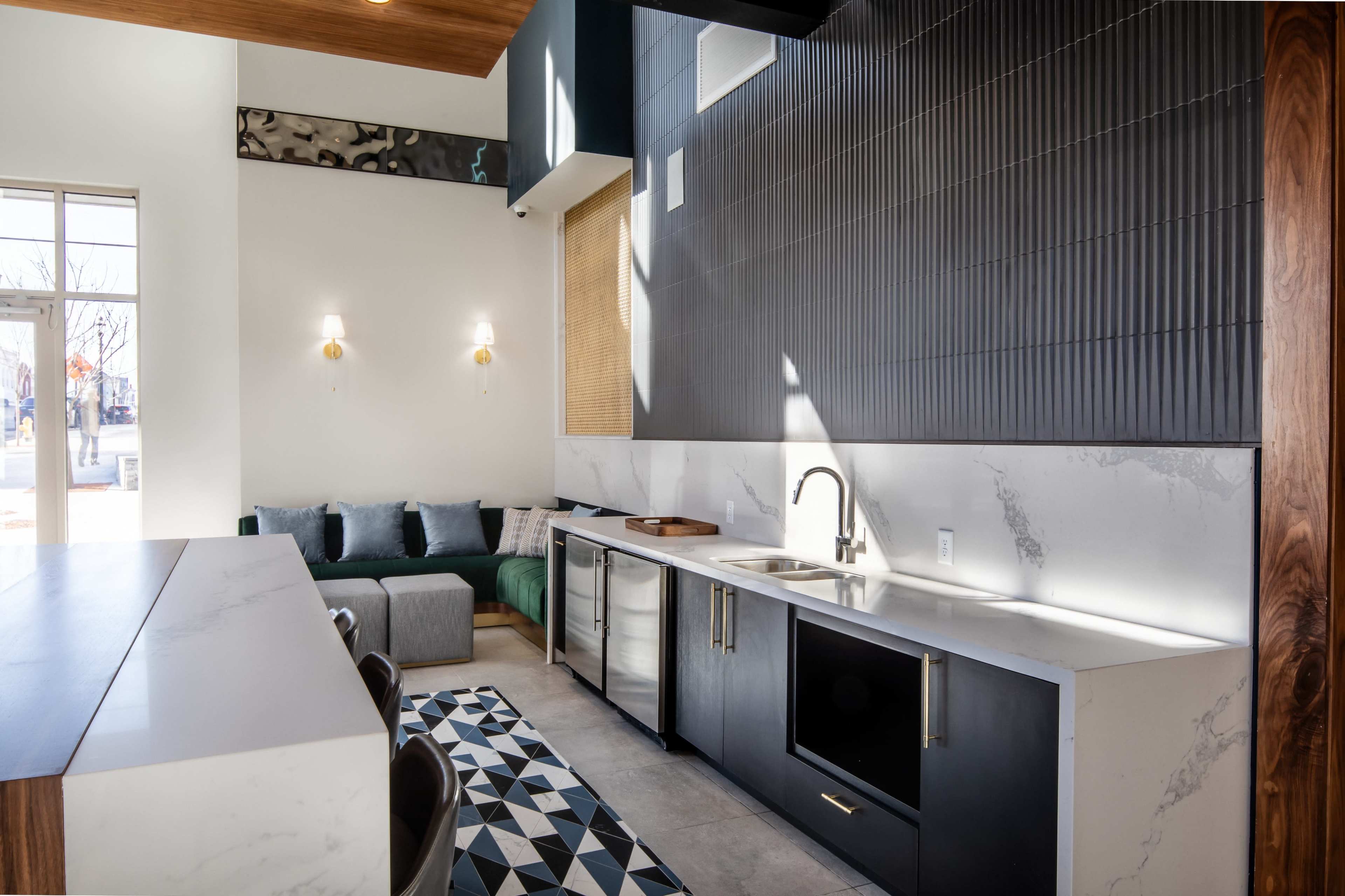 A modern kitchen and seating area with sleek cabinetry, a marble countertop, and a patterned rug.