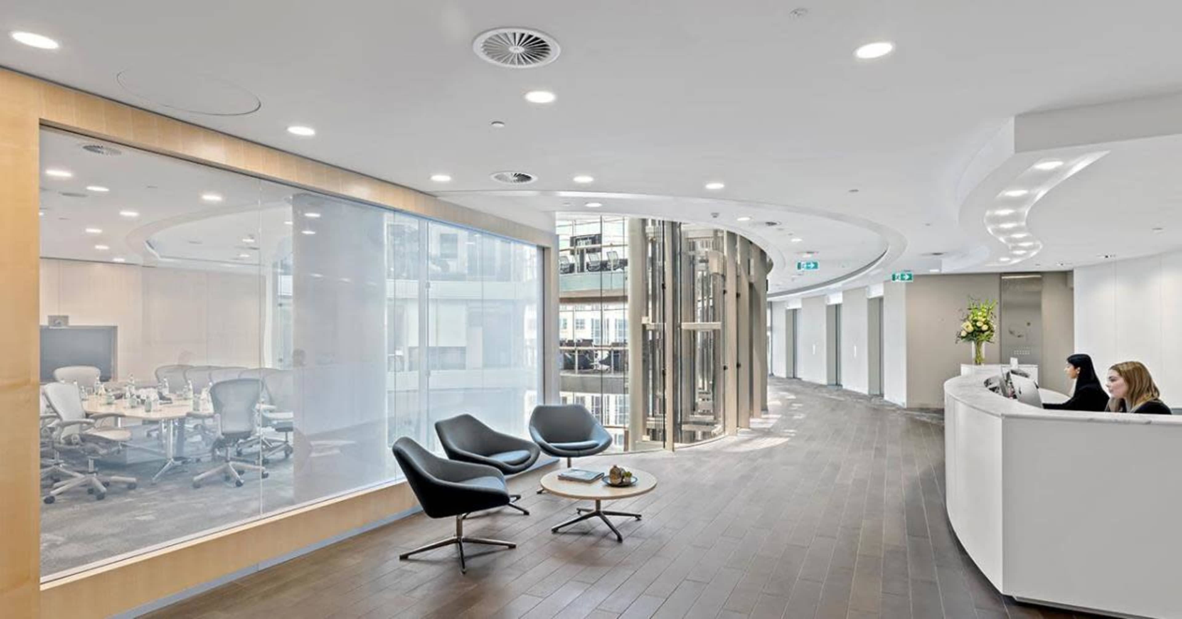A modern office lobby with curved walls, a reception area, and glass meeting rooms.