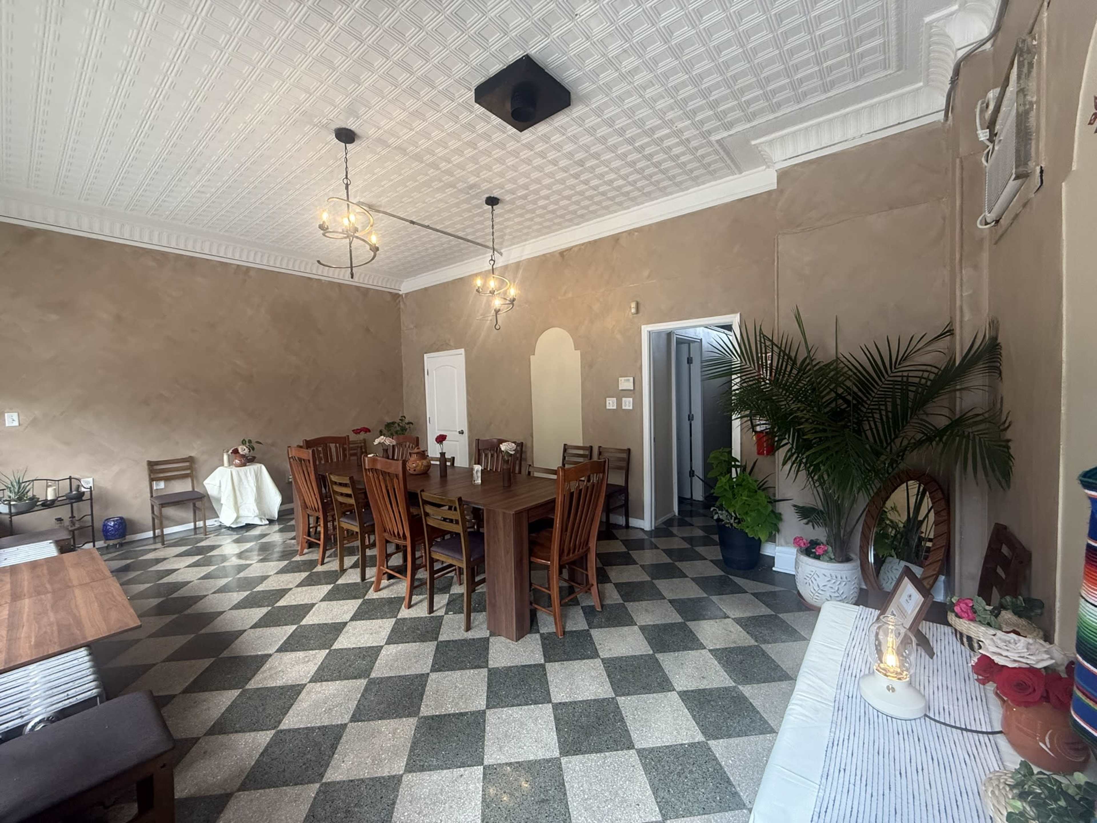 The image shows a dining room with a large wooden table and chairs, adorned with a patterned floor and decorative wall features.