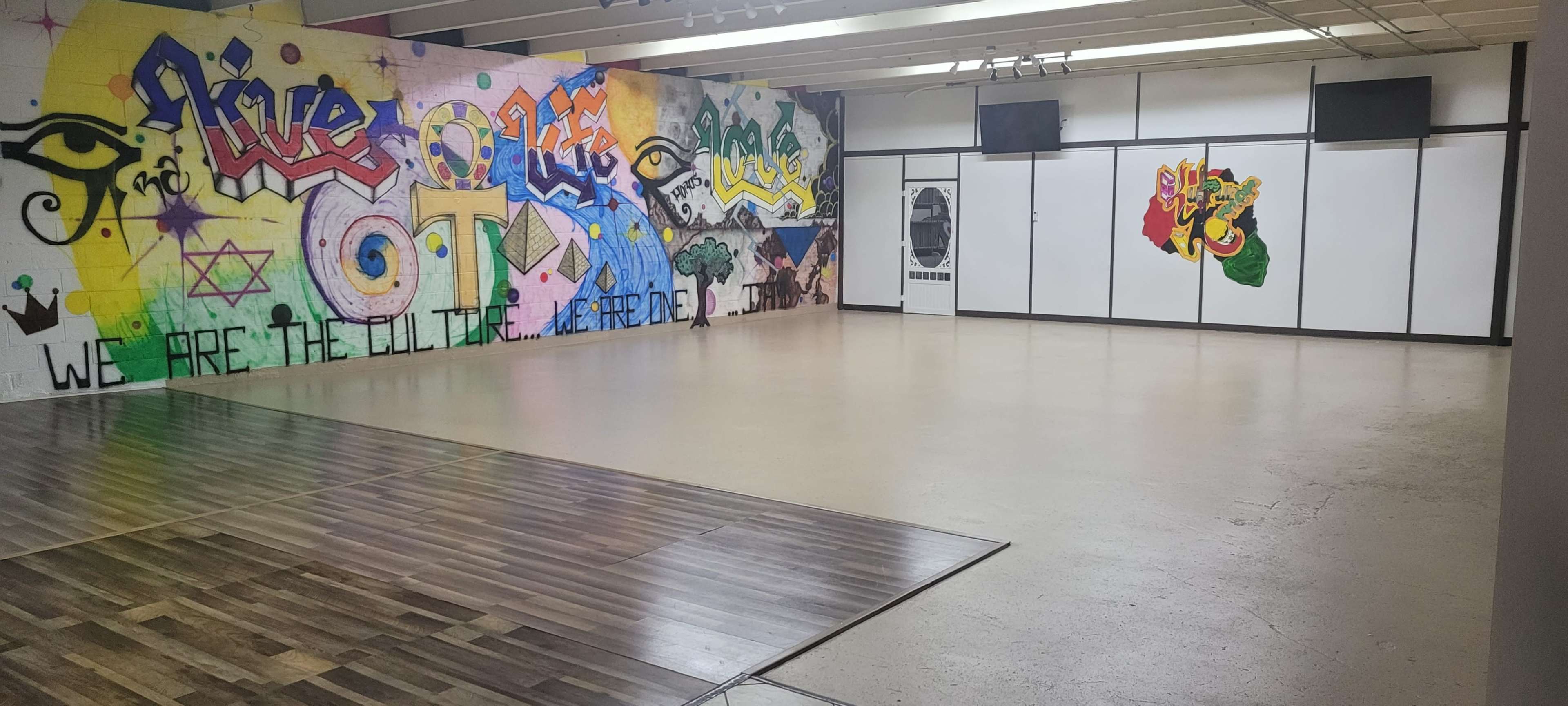 The image shows an empty room with graffiti-covered walls and a wooden floor.