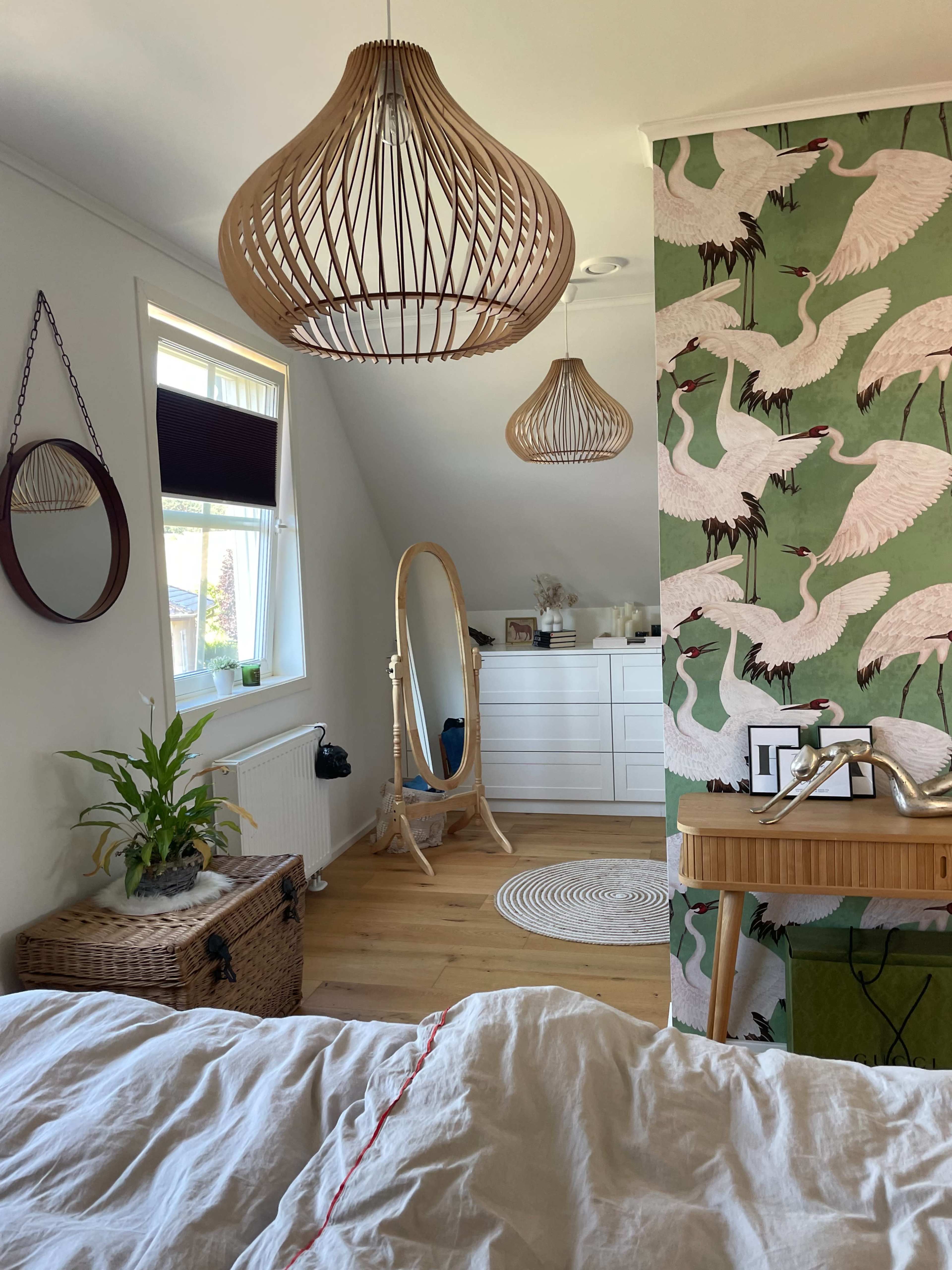 The room features two woven pendant lights, a full-length mirror, a dresser, and a wall adorned with a crane-patterned wallpaper.