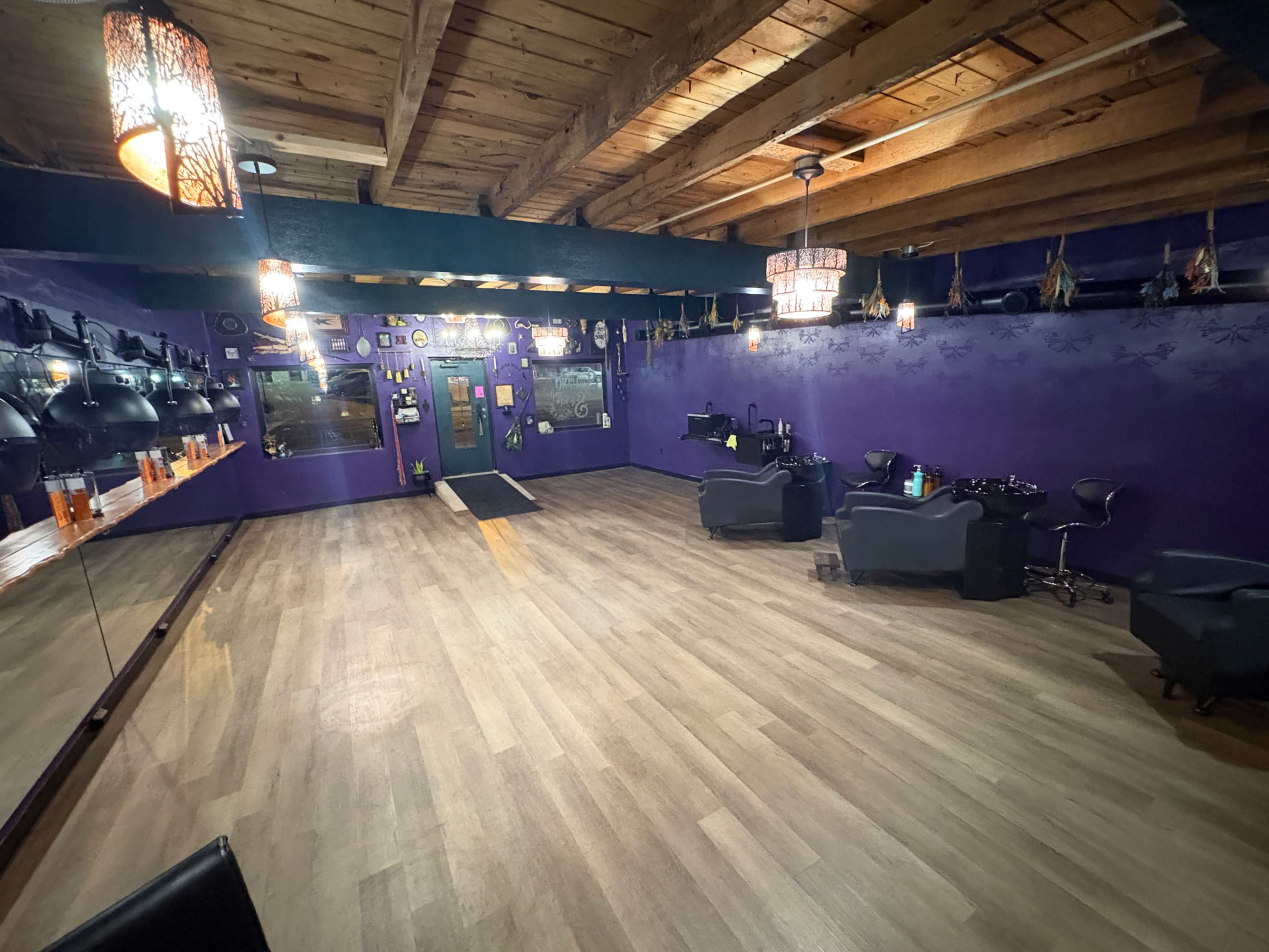 The image shows a spacious hair salon with purple walls, wooden beams overhead, and several styling stations with chairs and mirrors.