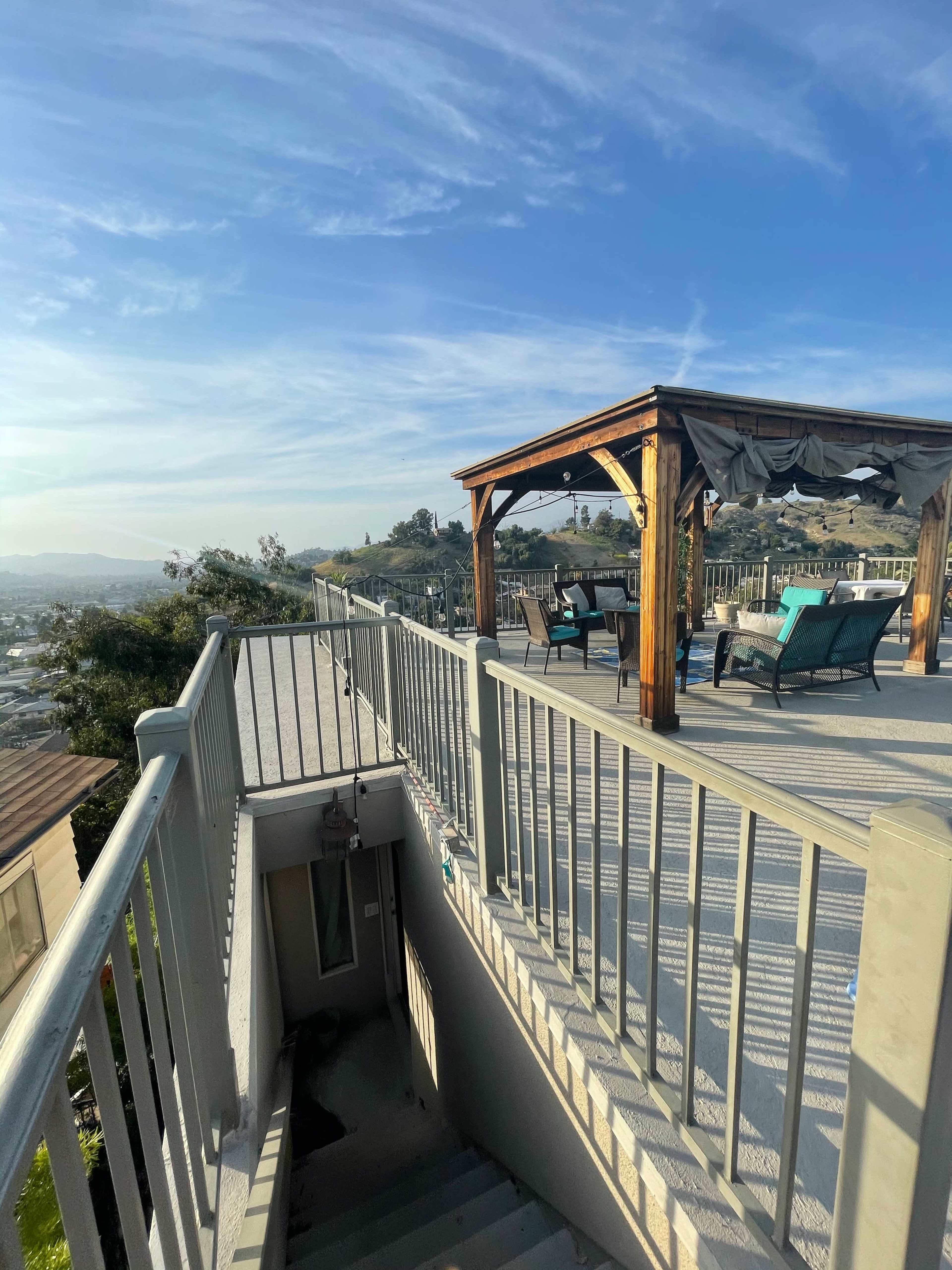 A staircase leading down from a wooden deck with seating areas and a view of the landscape.