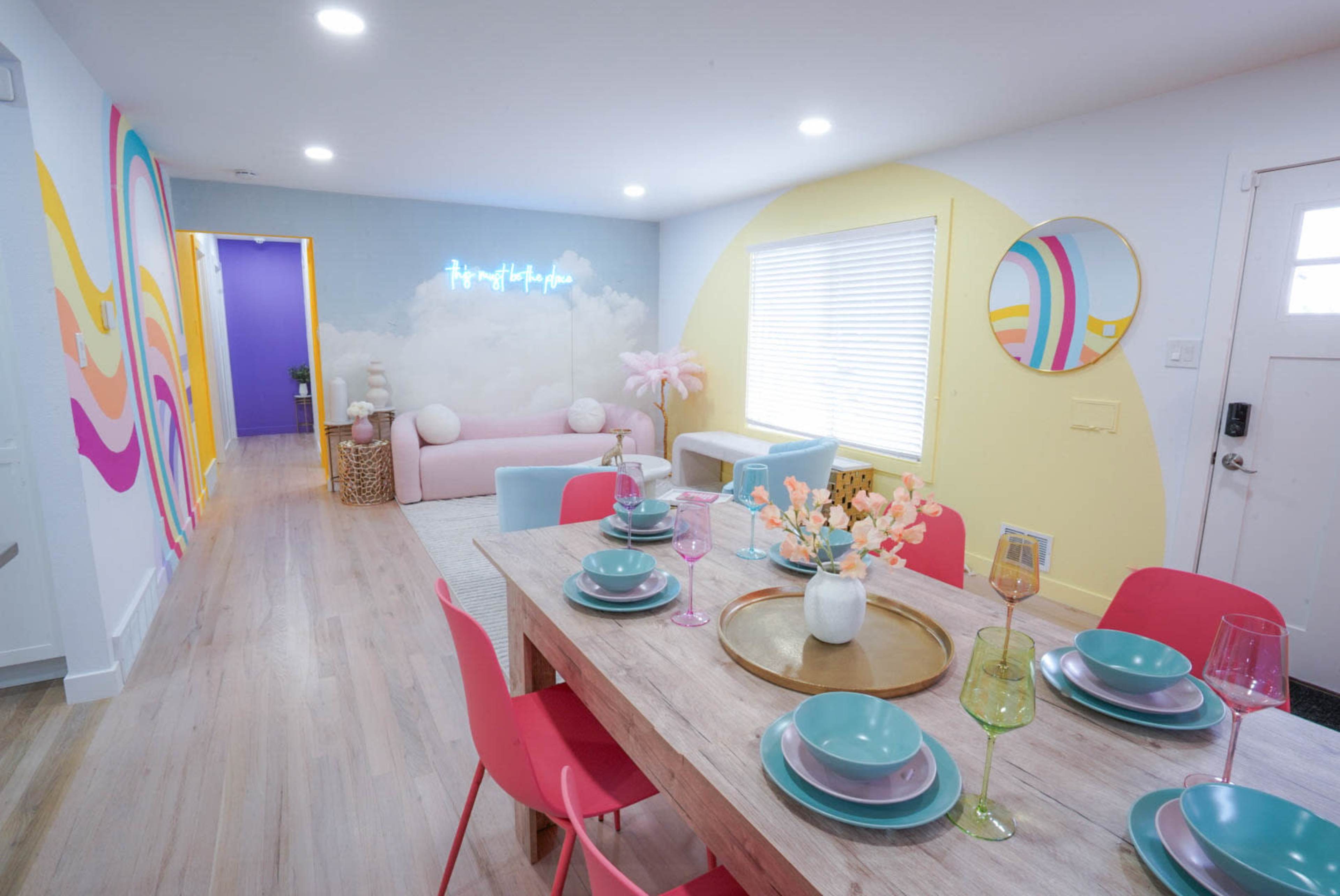 A brightly decorated living area with a dining table set for a meal and a pastel-colored couch in the background.