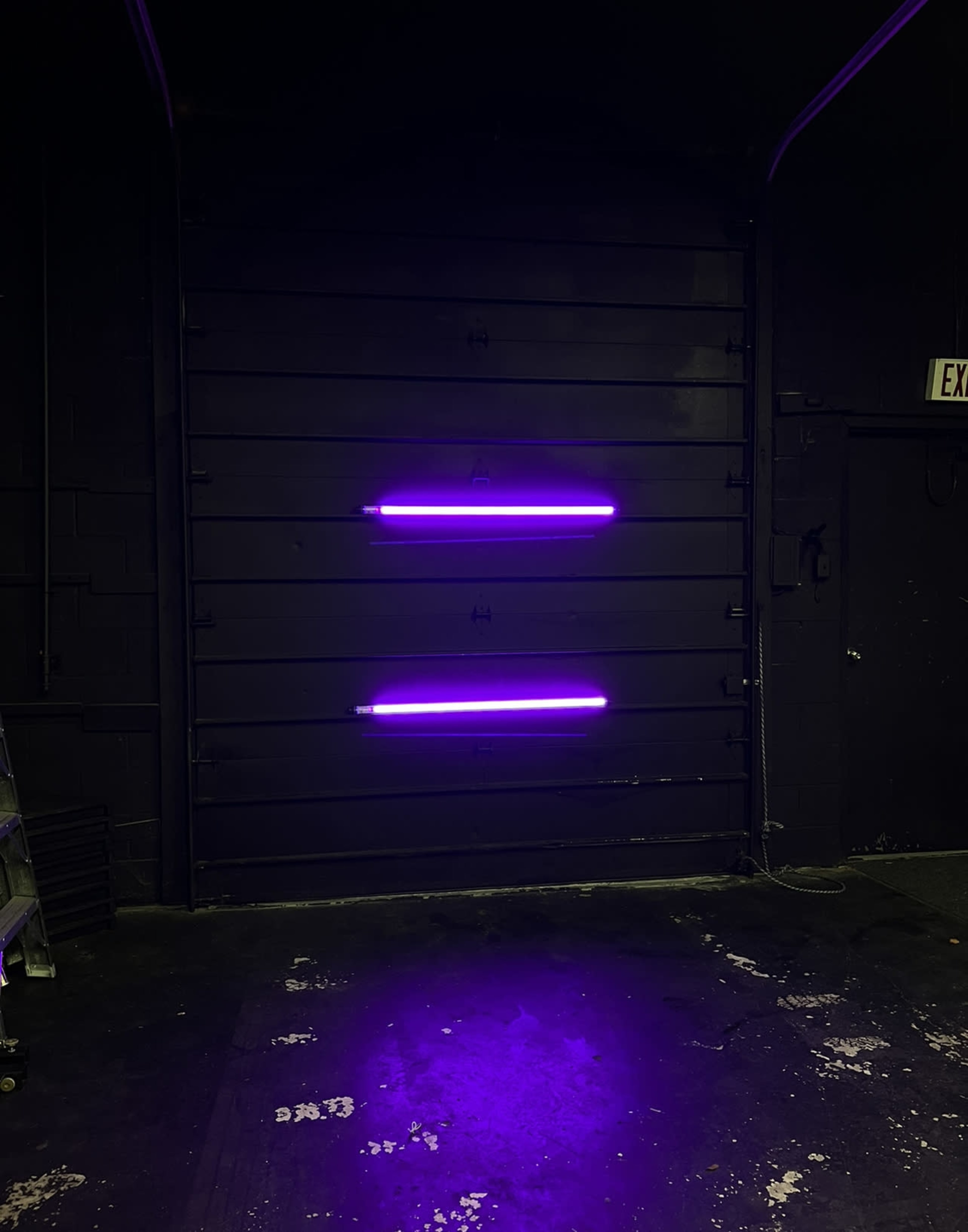 A black wall features two horizontal purple neon lights above the ground.