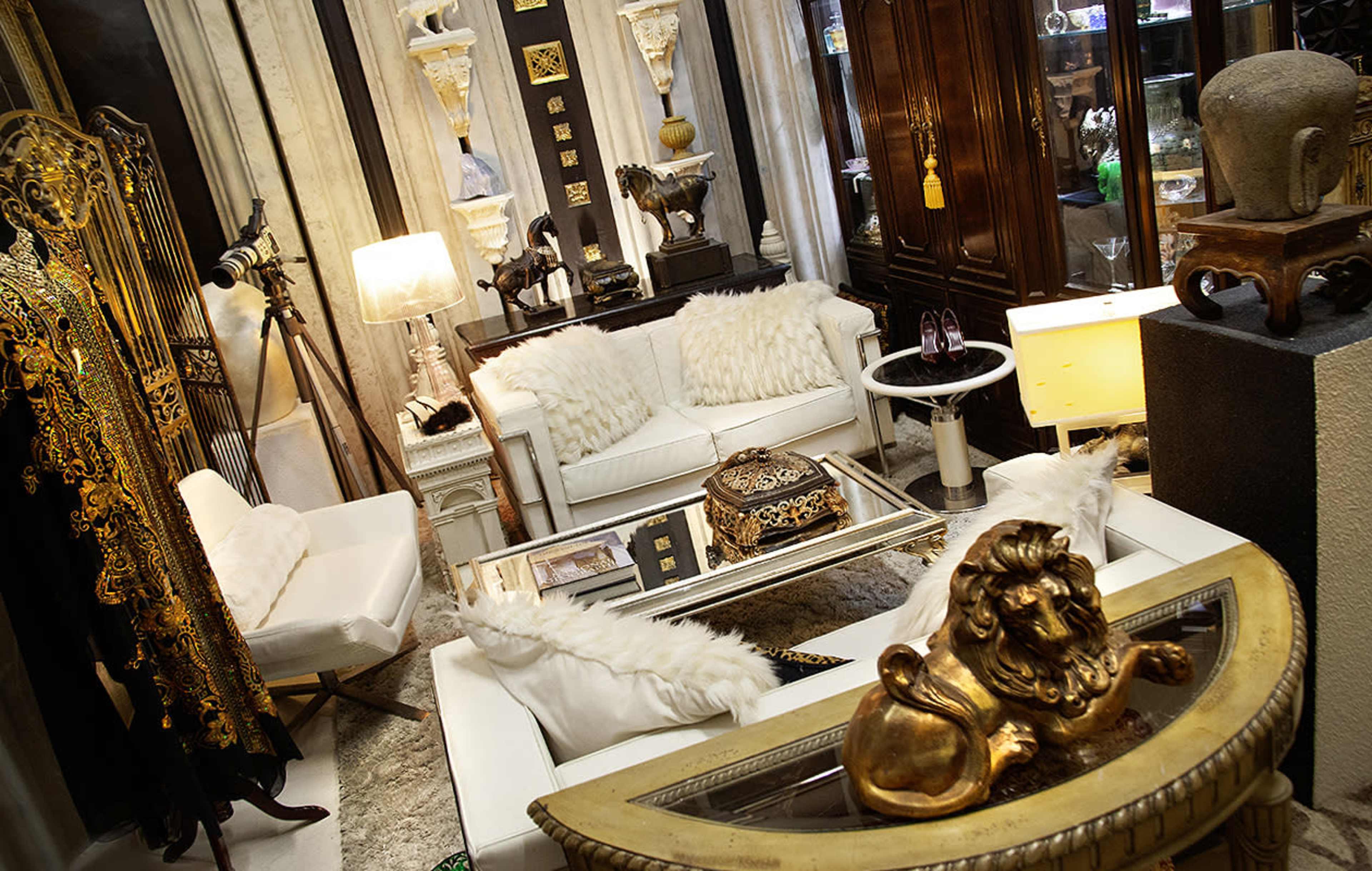 The image depicts a beautifully arranged living space featuring white furniture, ornate decorations, and various decorative artifacts displayed within a well-lit room.