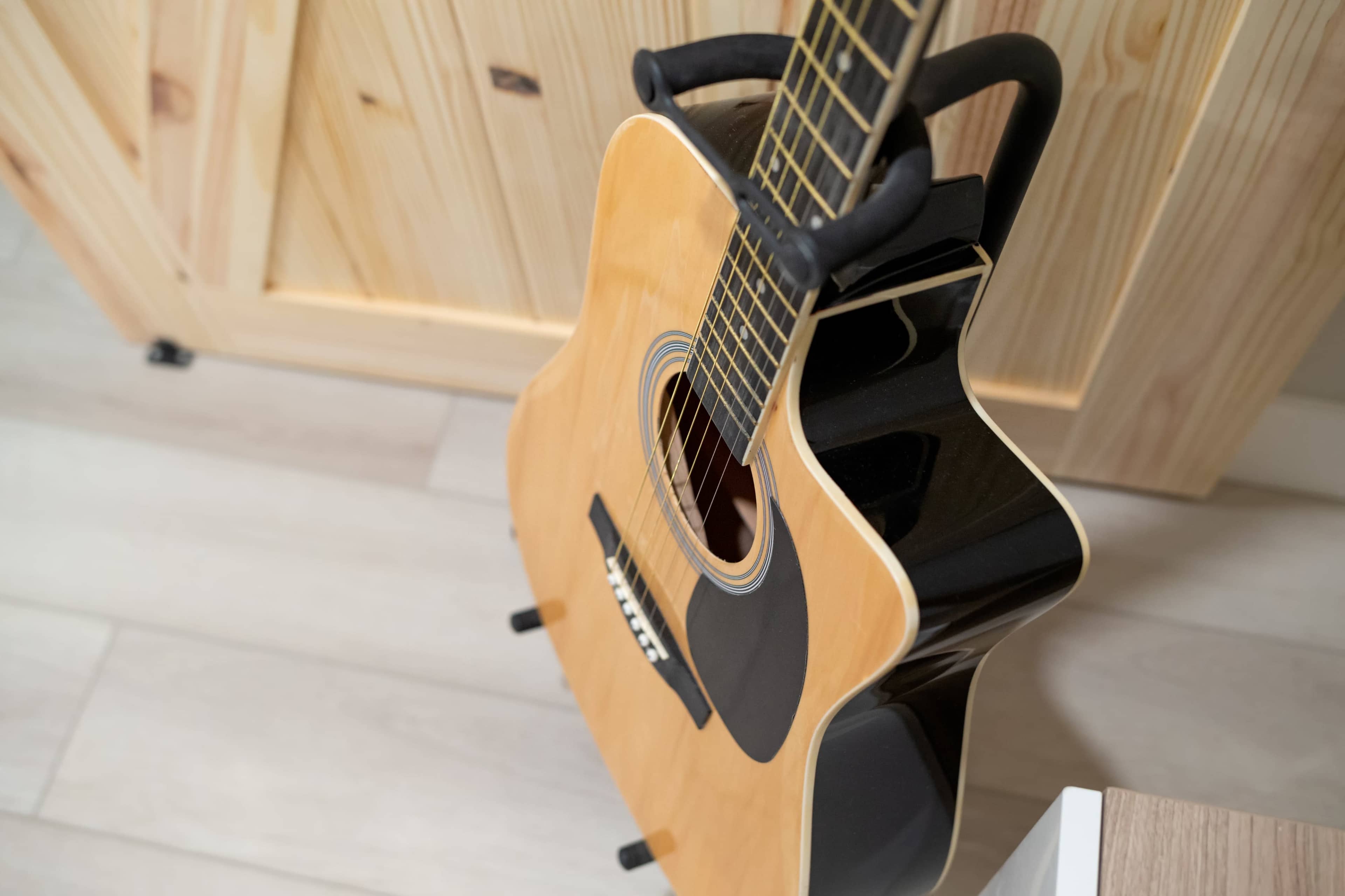 An acoustic guitar is resting on a stand in a room with wooden features.