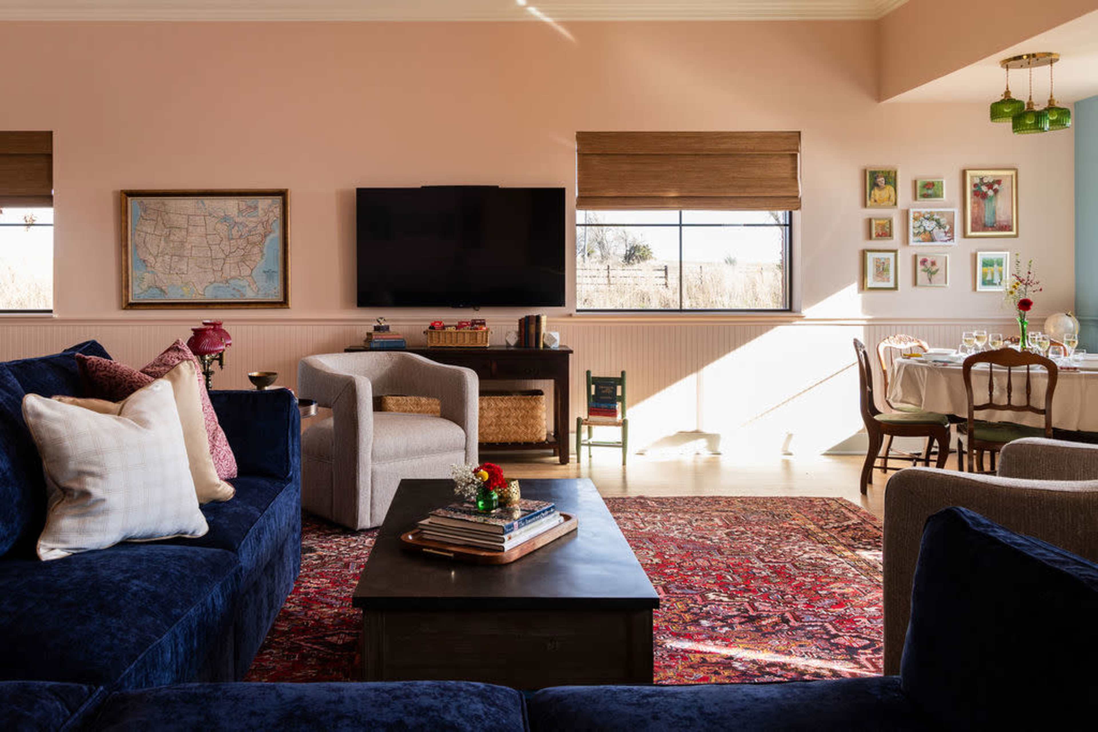 A cozy living room features a navy blue sofa, a wooden coffee table, and a television mounted on the wall, with a dining area visible in the background.