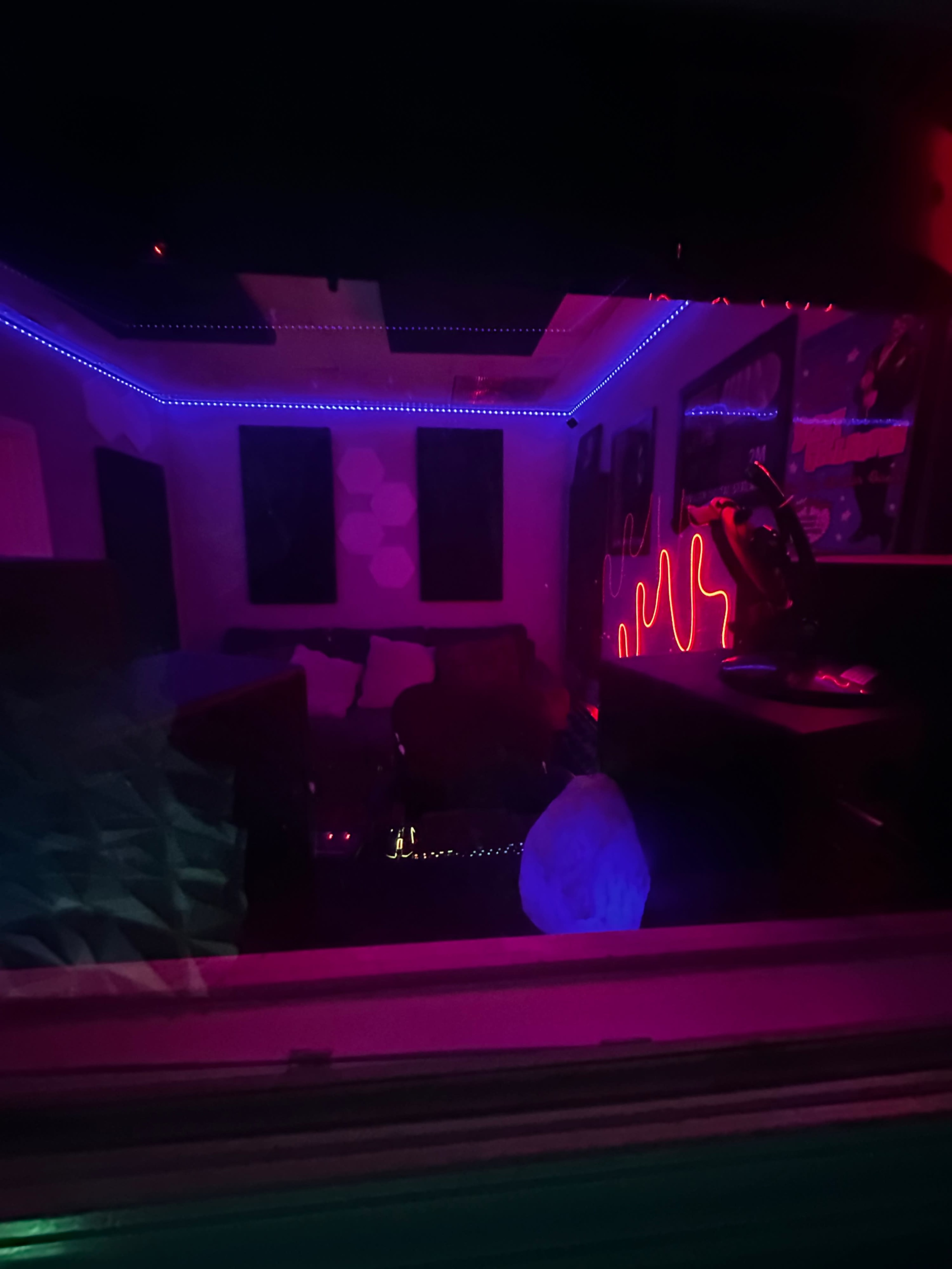 The image shows a dimly lit room with colorful neon lighting and modern furniture.