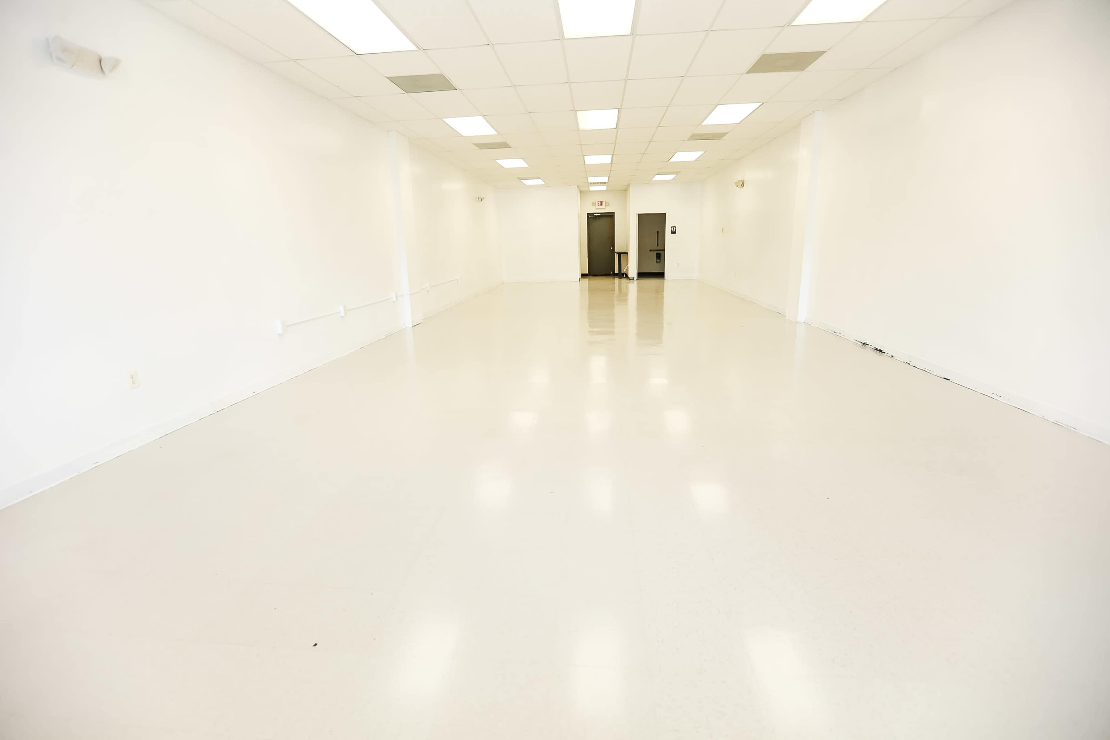 A large, empty room with white walls and a bright, glossy floor.