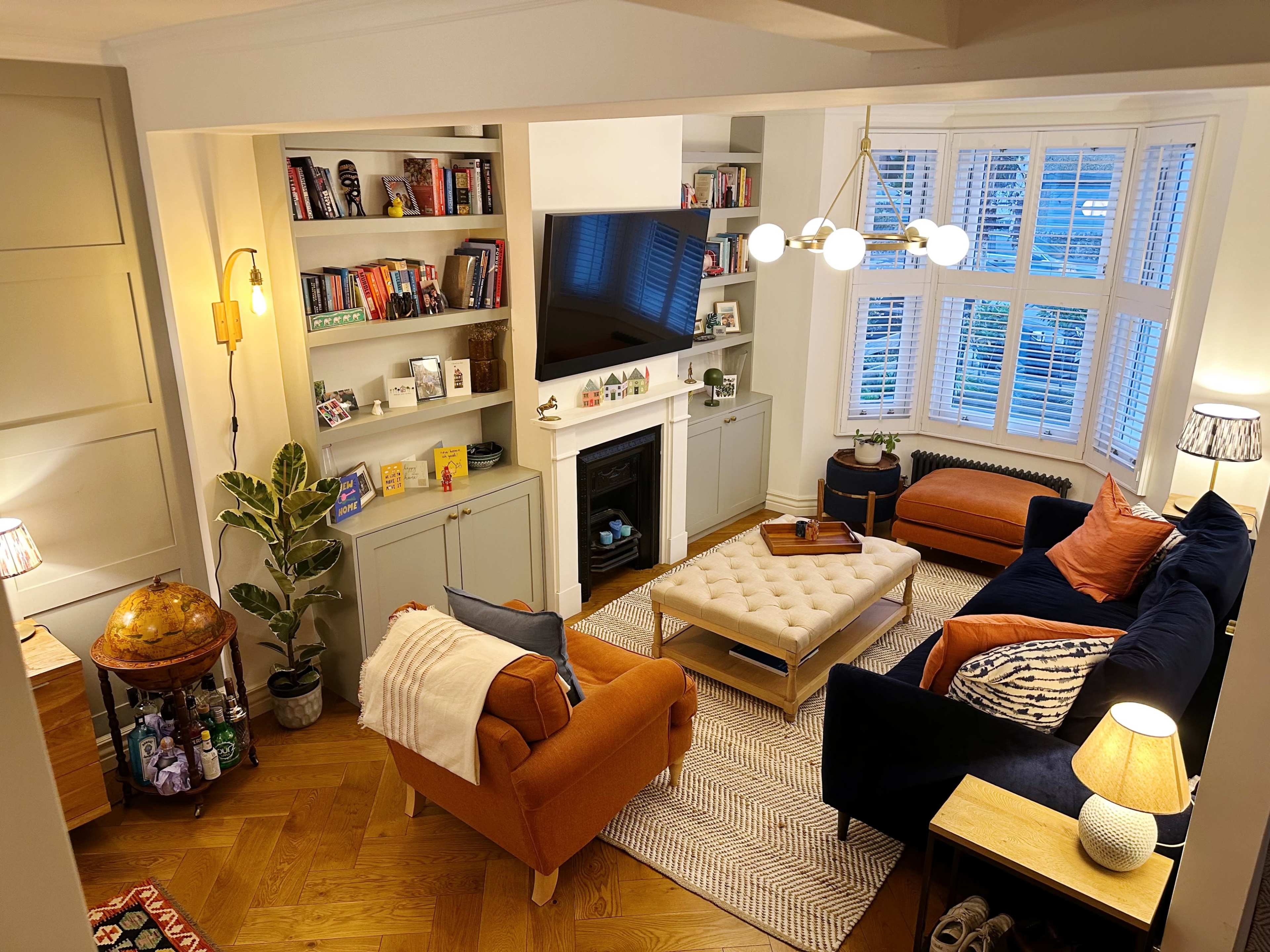 The image shows a cozy living room featuring a mix of comfortable seating, a coffee table in the center, and built-in shelves filled with books and decorative items.