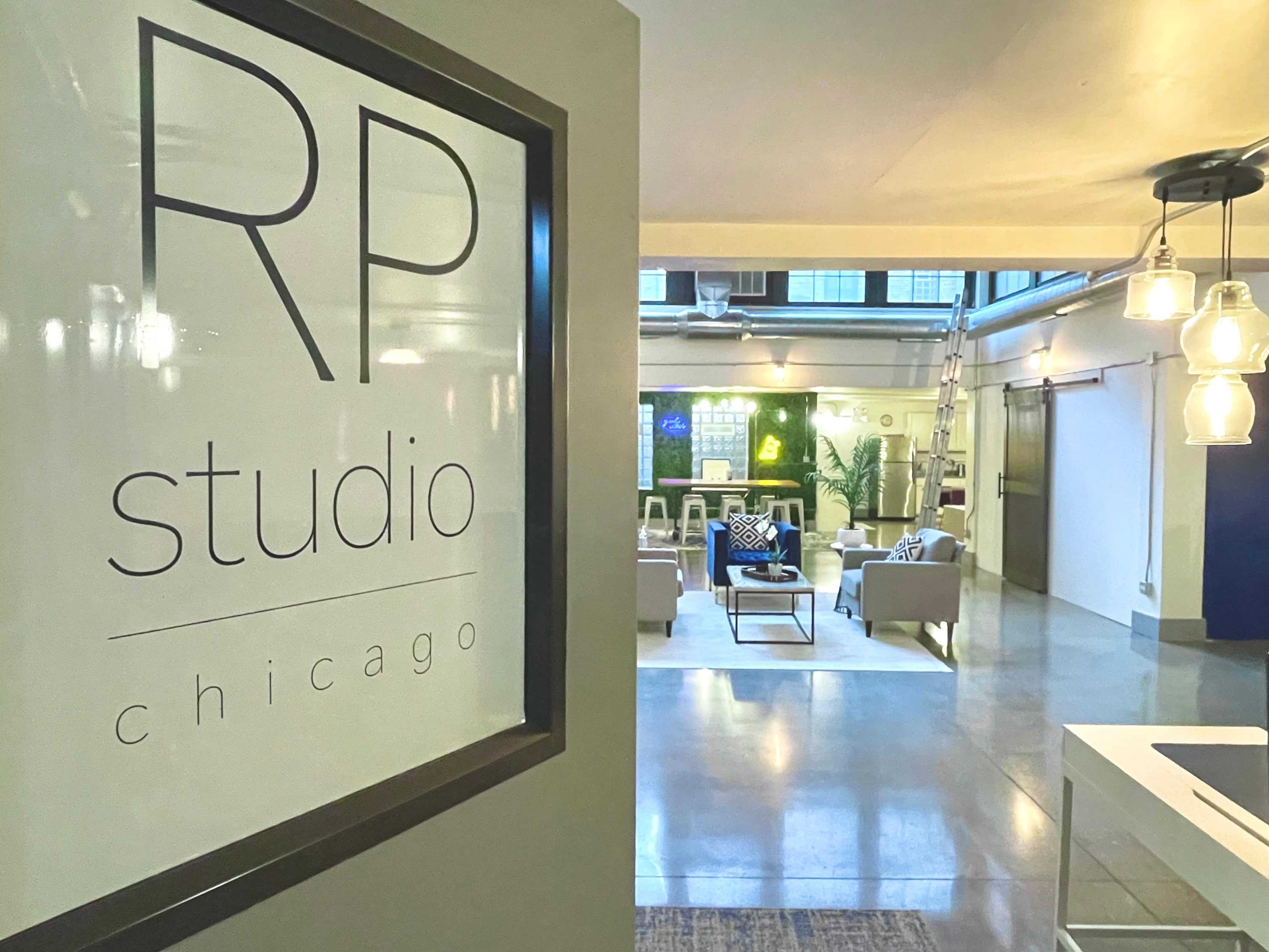 A sign reading "RP studio Chicago" is positioned next to an open interior space featuring seating areas and large windows.