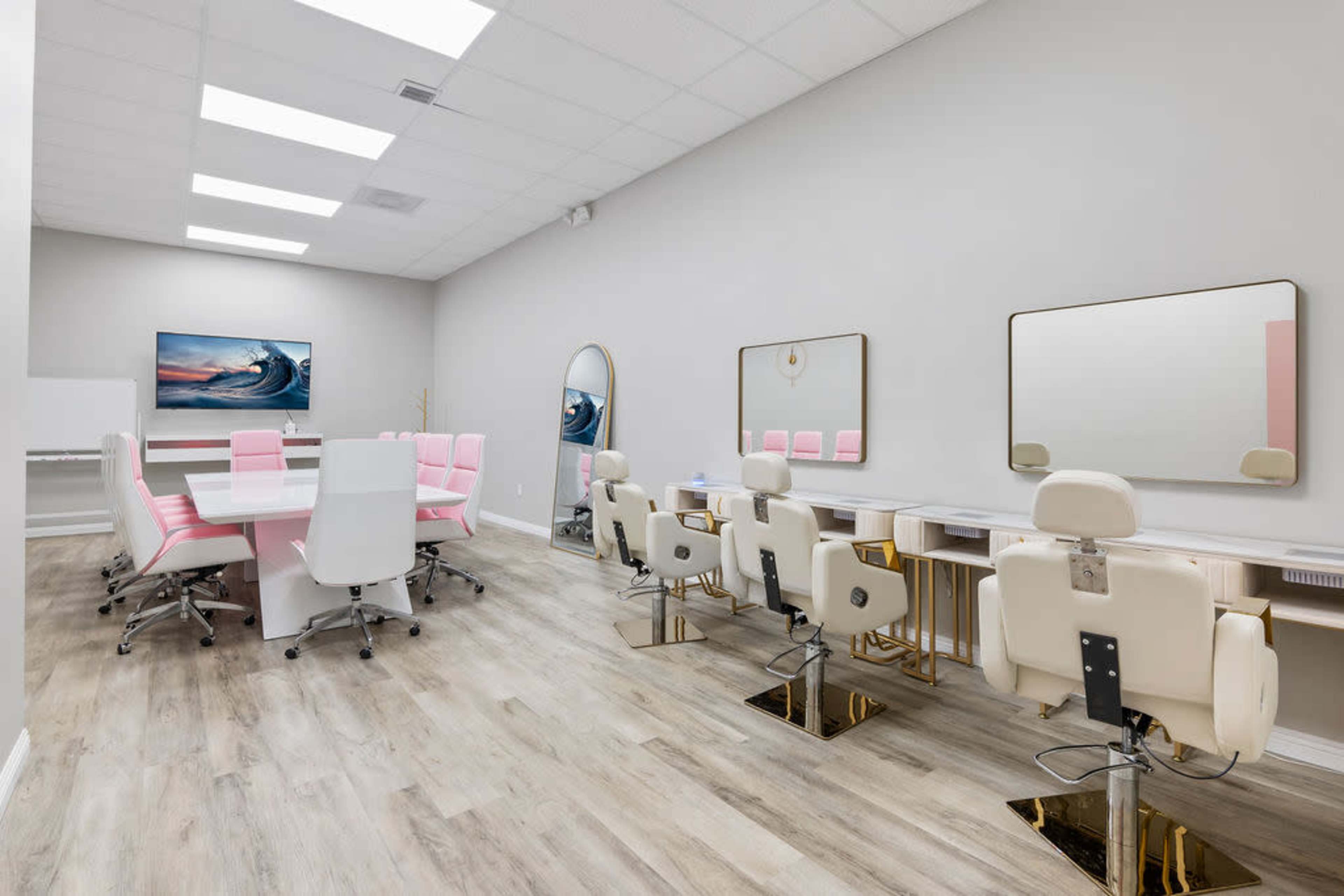 A modern salon interior featuring a large table for consultations, several styling stations with mirrors, and a neutral color scheme.