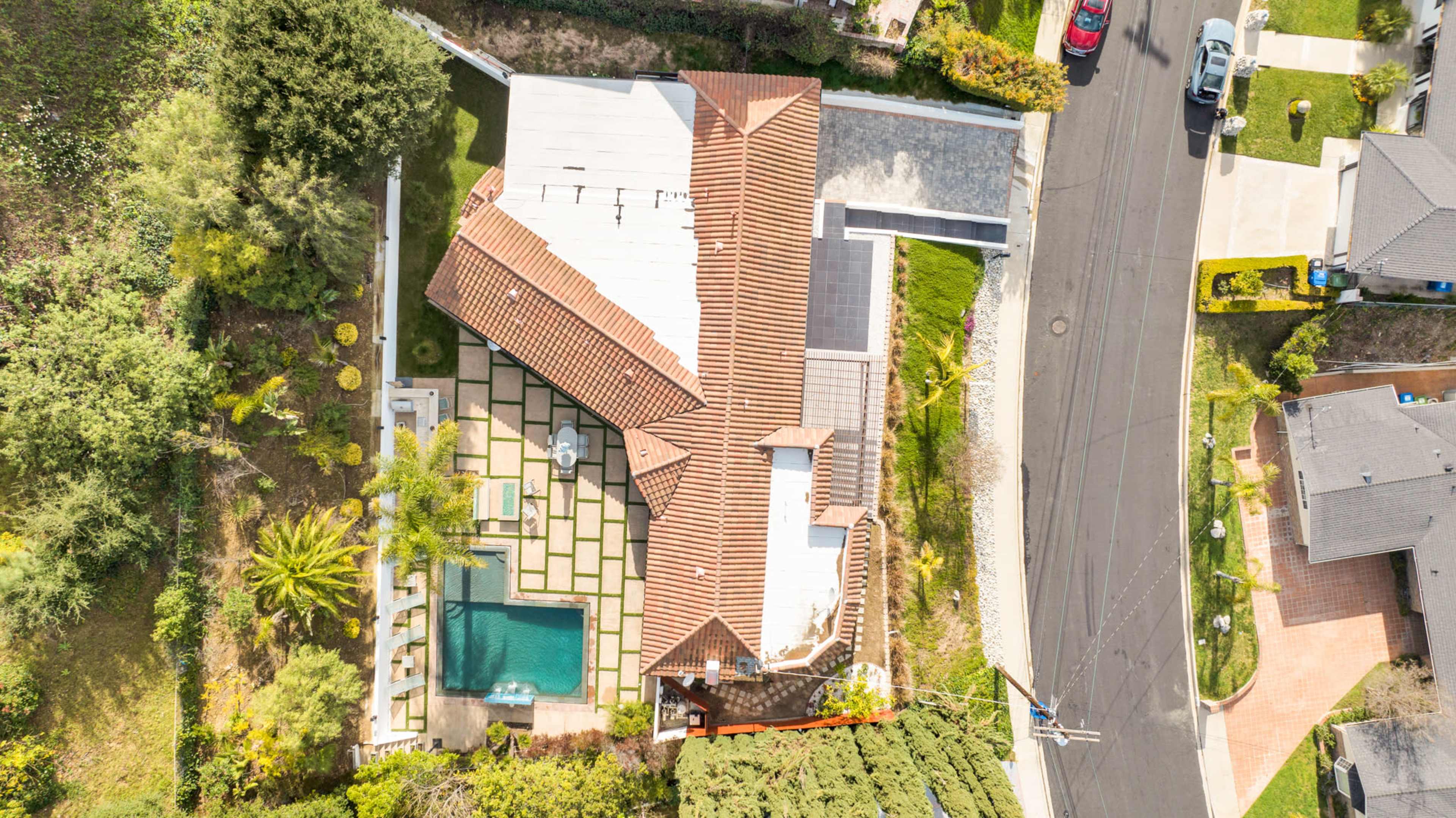 The image shows a residential property with a pool, landscaped yard, and a tile-roofed house, viewed from above.