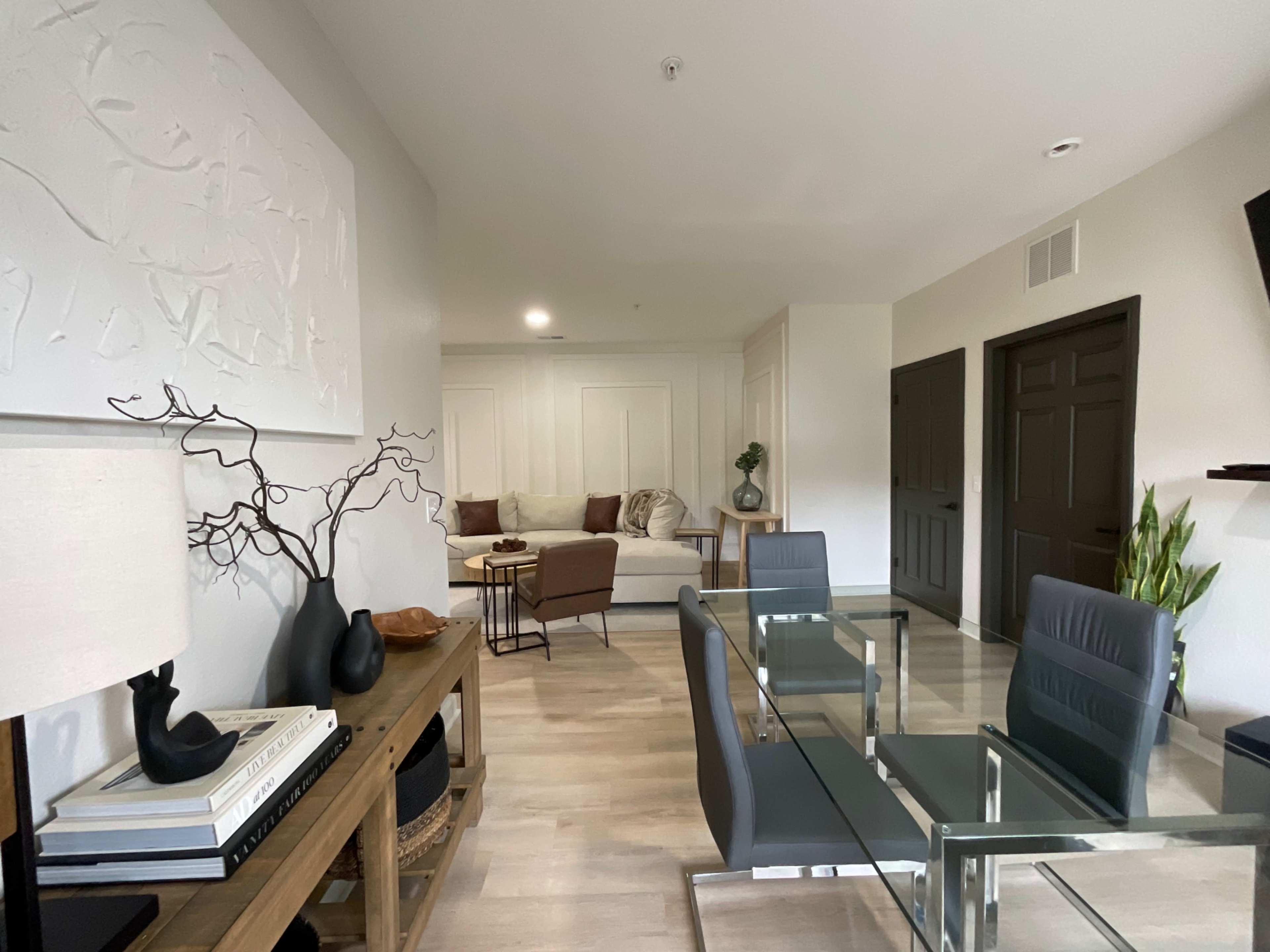 A modern living space featuring a seating area with a sofa, a dining table, and a minimalist decor style.
