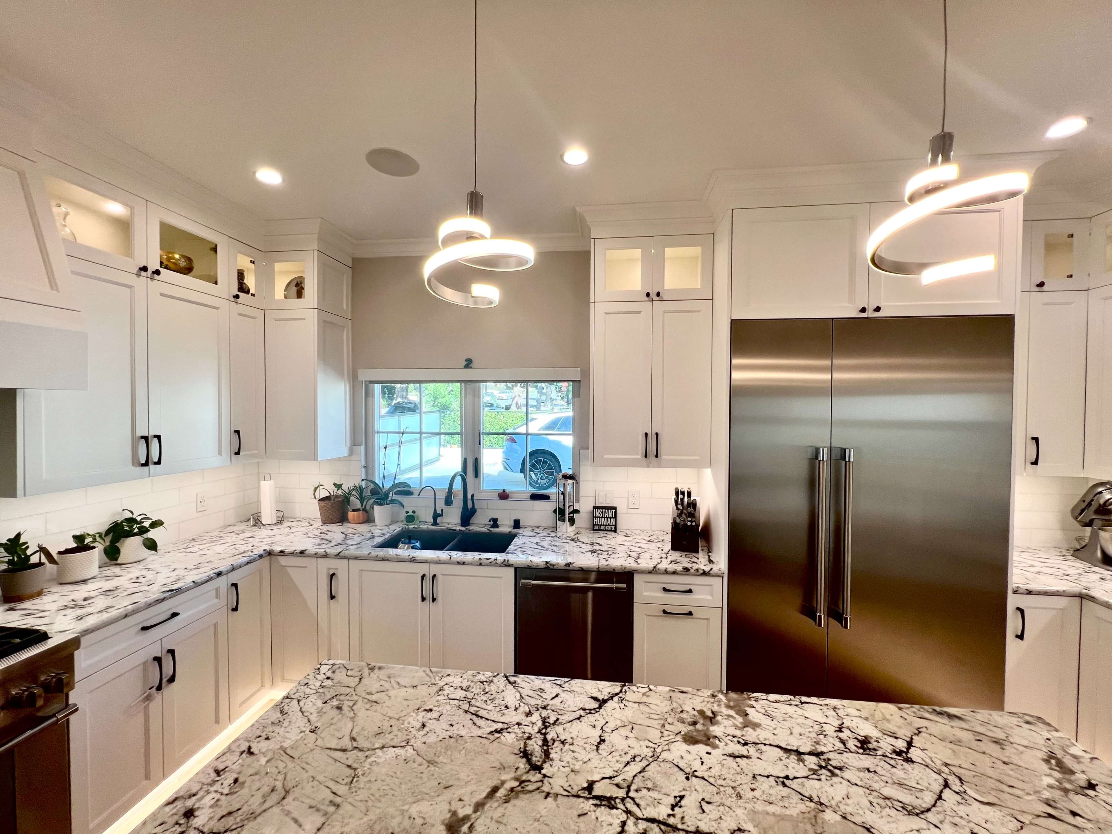 The kitchen features countertop and cabinetry with a white finish, stainless steel appliances, and modern light fixtures.