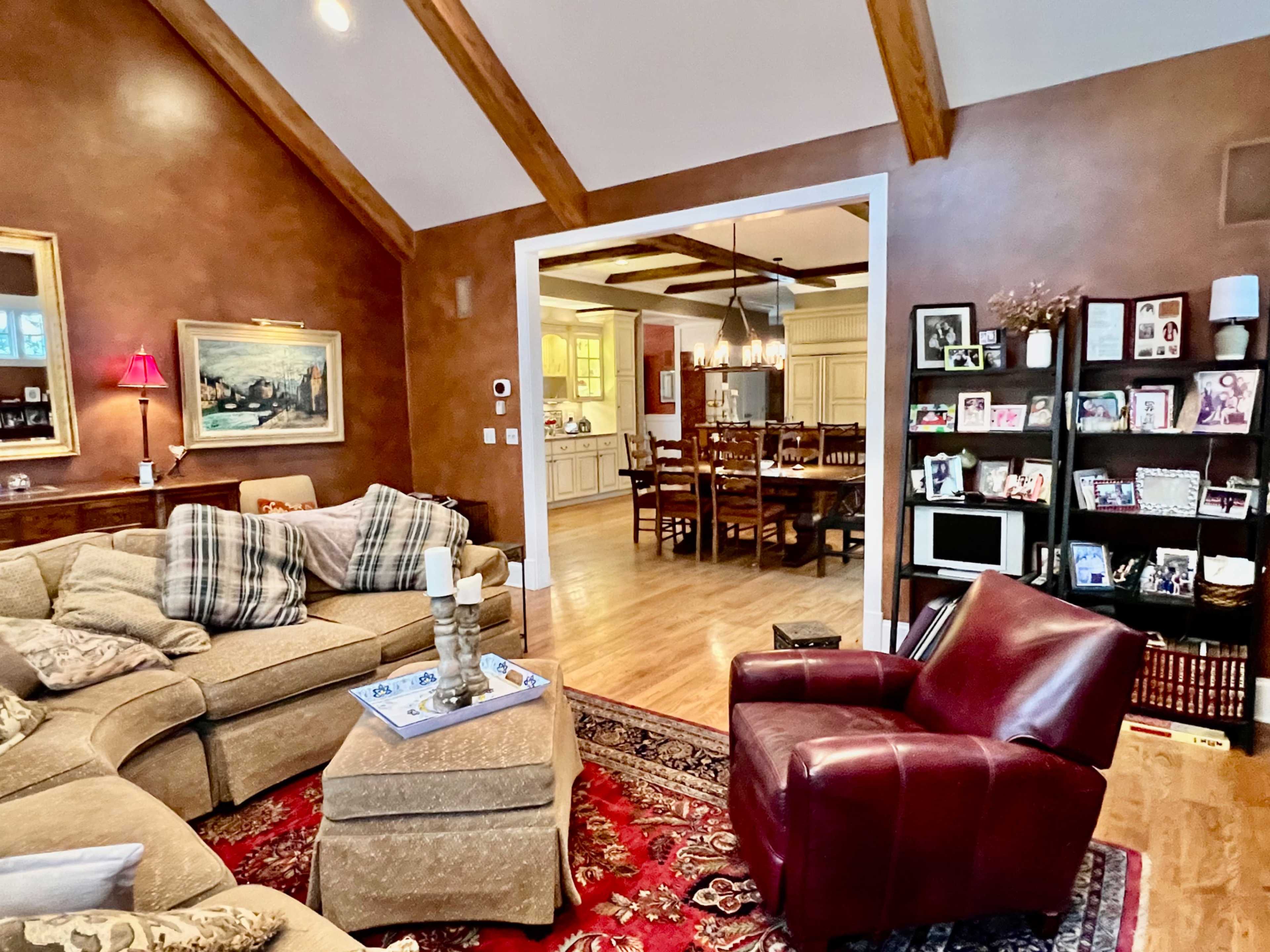 A cozy living room with a sectional sofa, a red recliner, and a view into a dining area with wooden furniture.